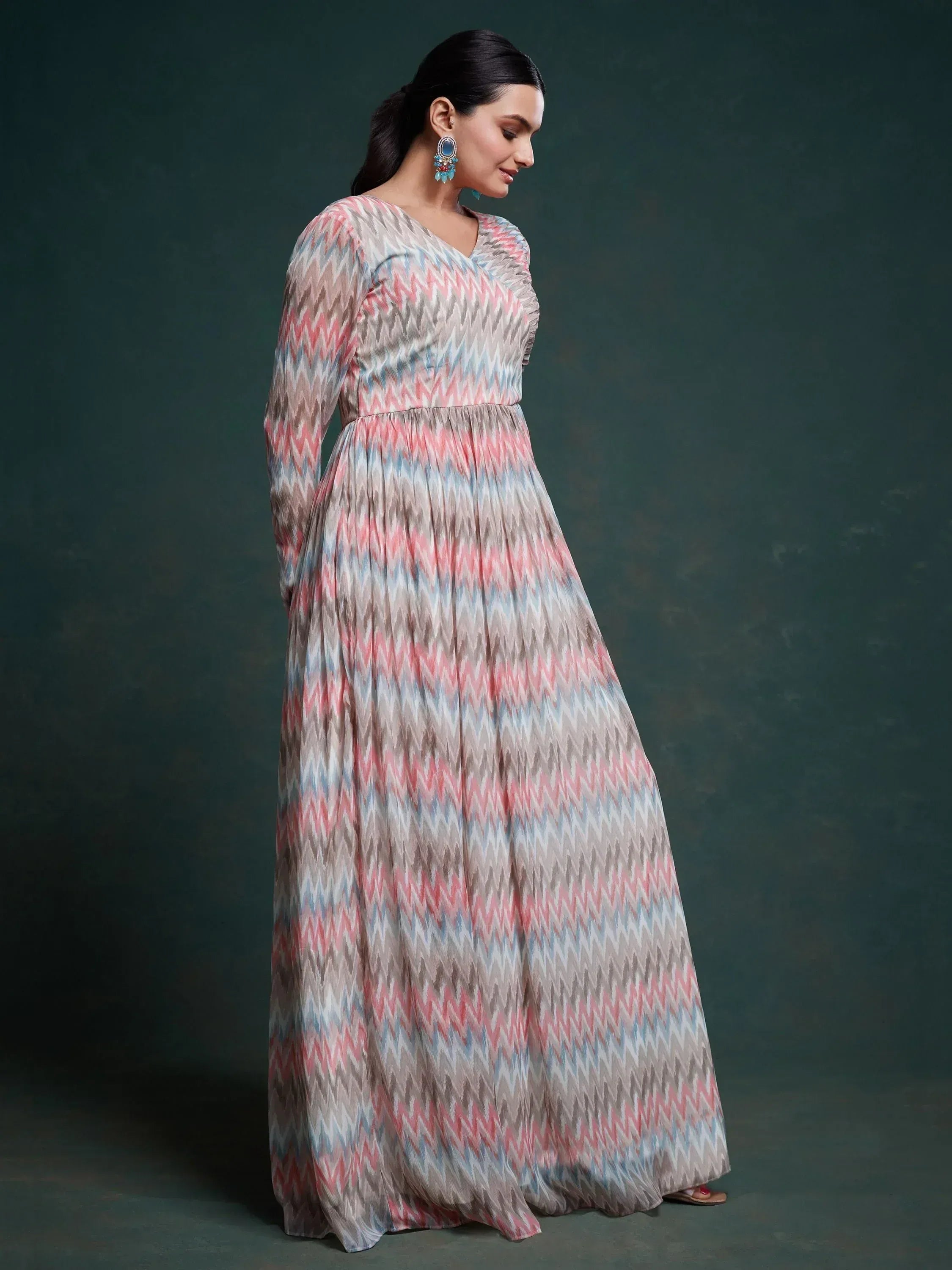 Woman in full-length zigzag print ethnic gown with pastel pink, blue and beige pattern