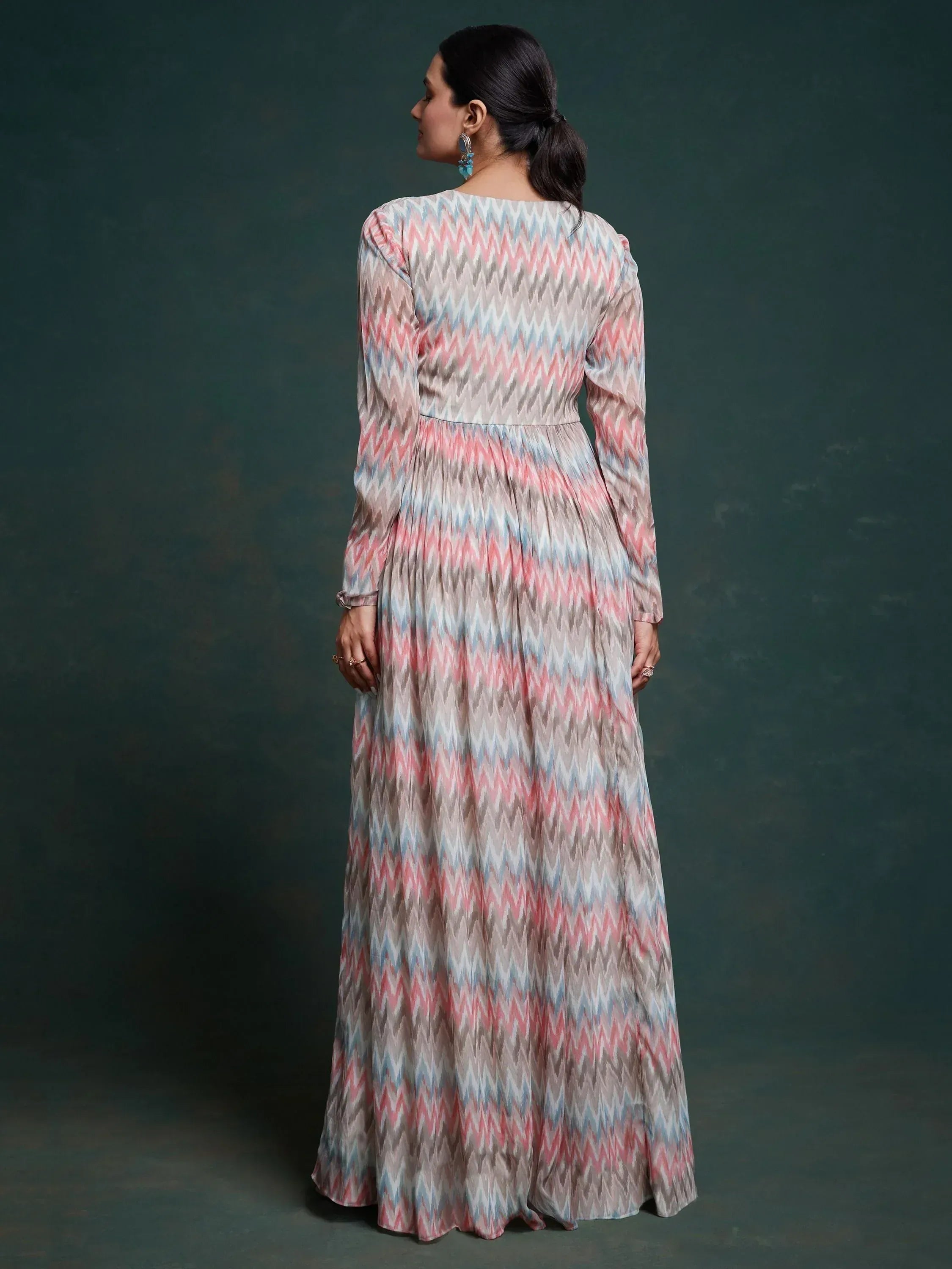 Woman wearing long ethnic gown with pastel zigzag print and long sleeves, rear view