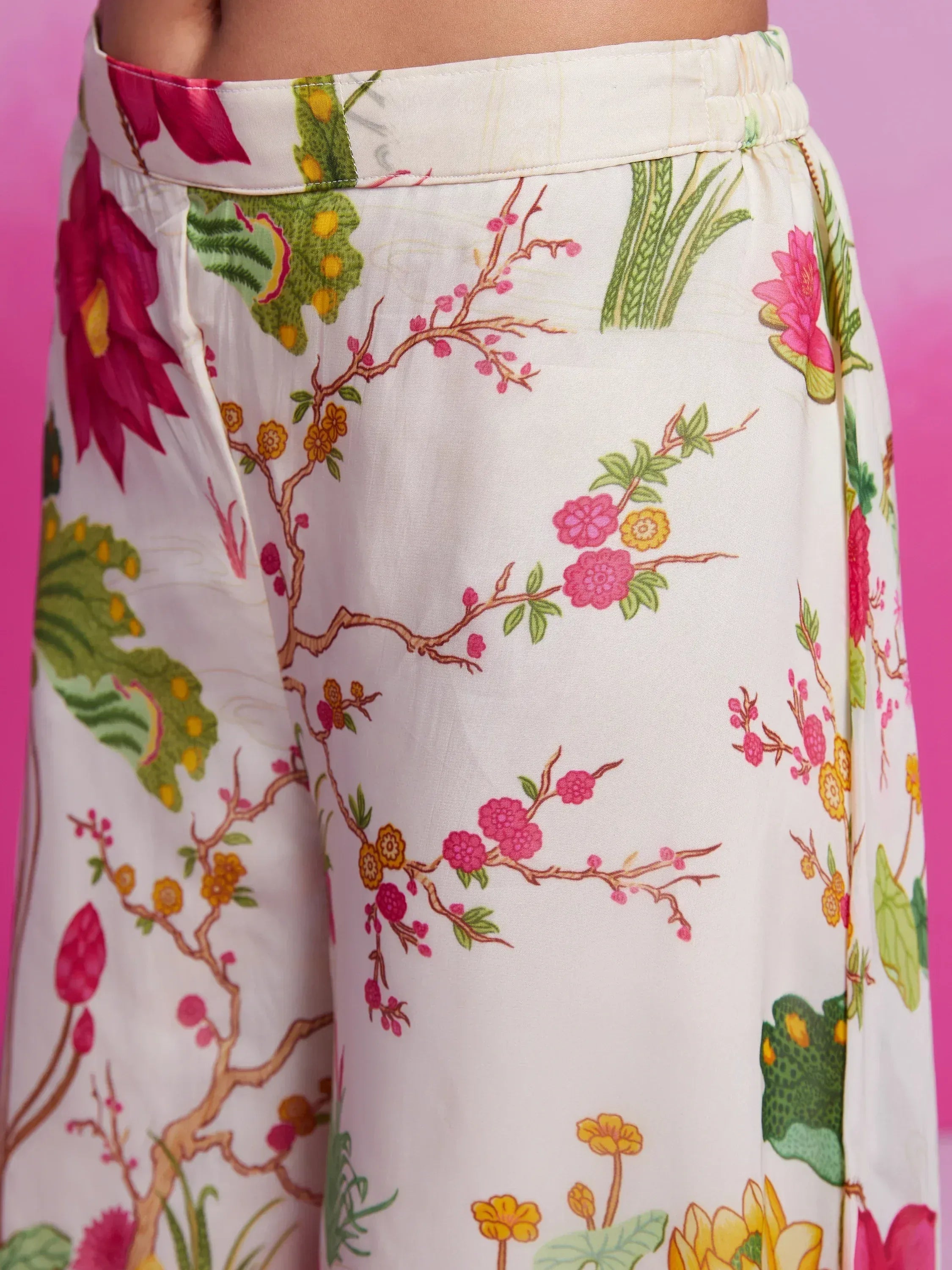 Floral print palazzo pants with elastic waist, vibrant pink and green botanical design on cream fabric
