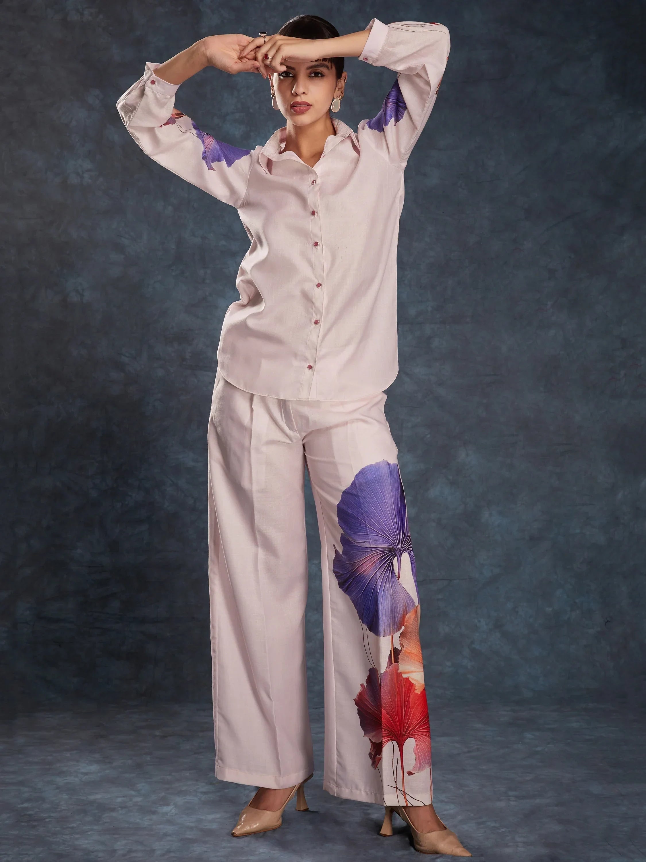 Woman wearing light pink co-ord set with floral print wide-leg pants and button-up shirt