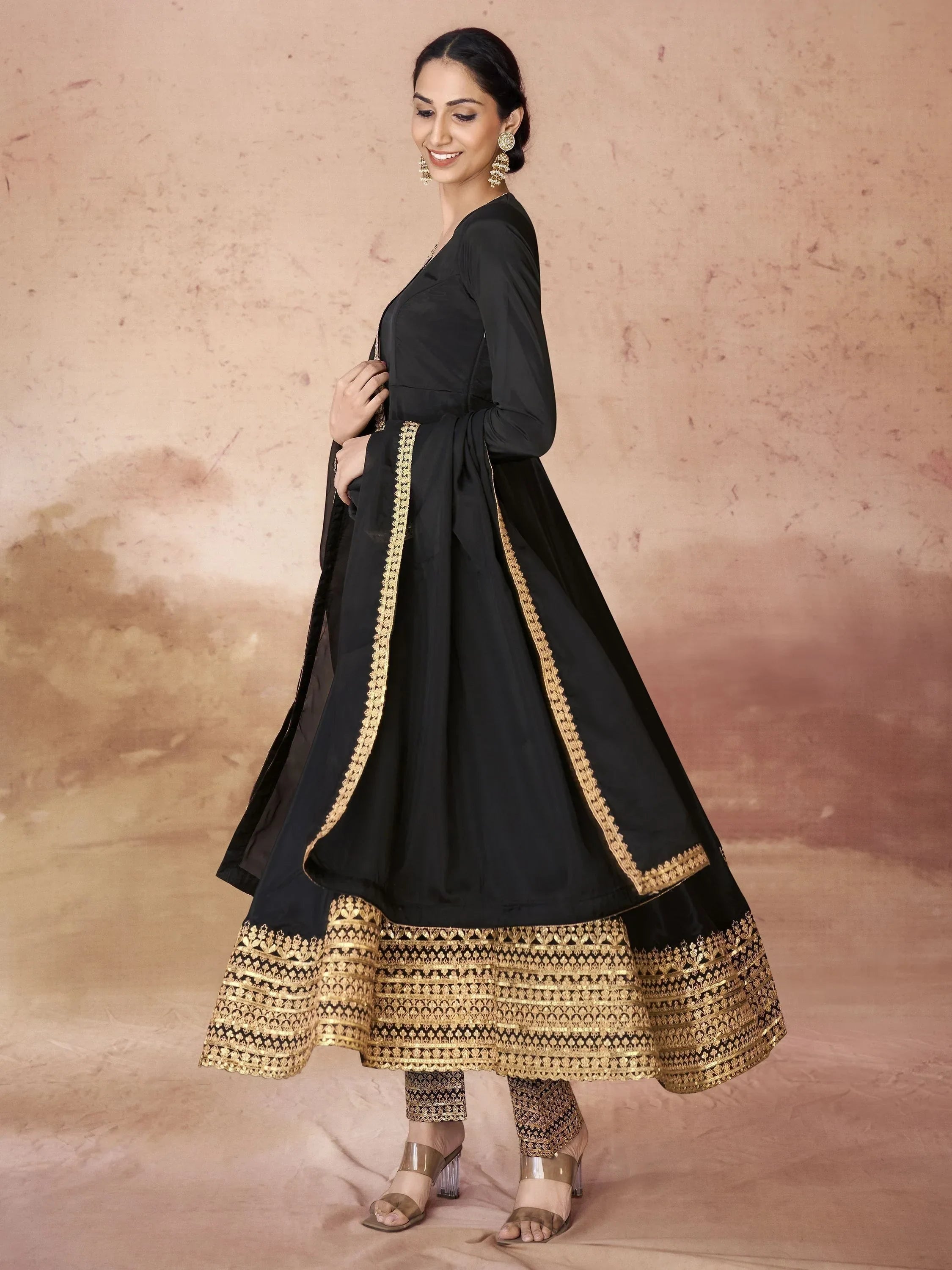 Woman wearing a black and gold embroidered Anarkali suit with dupatta and ethnic jewelry