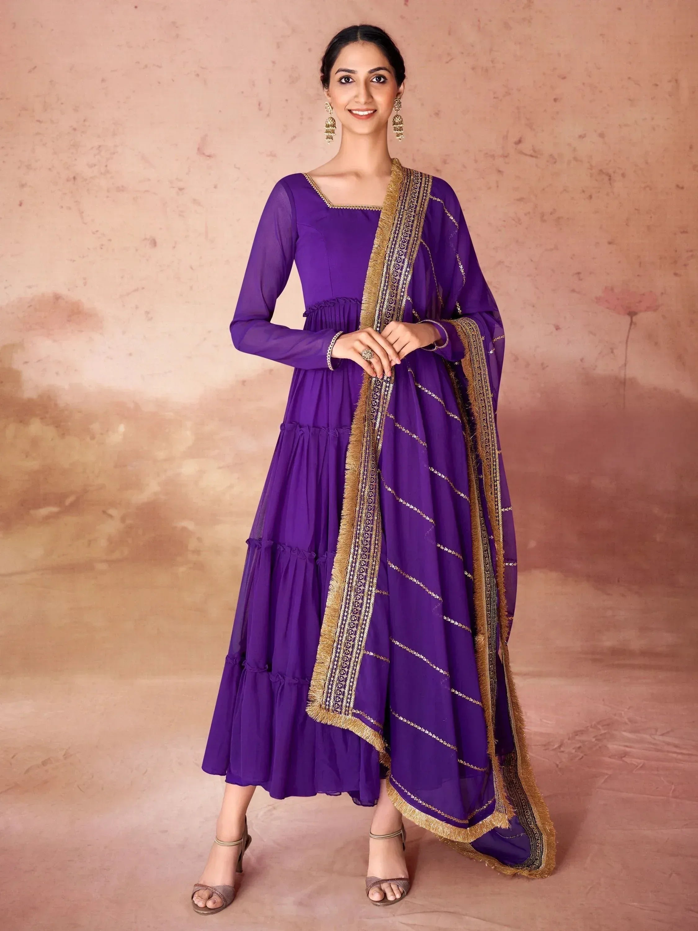 Woman wearing purple ethnic gown with gold embroidered dupatta, traditional Indian attire