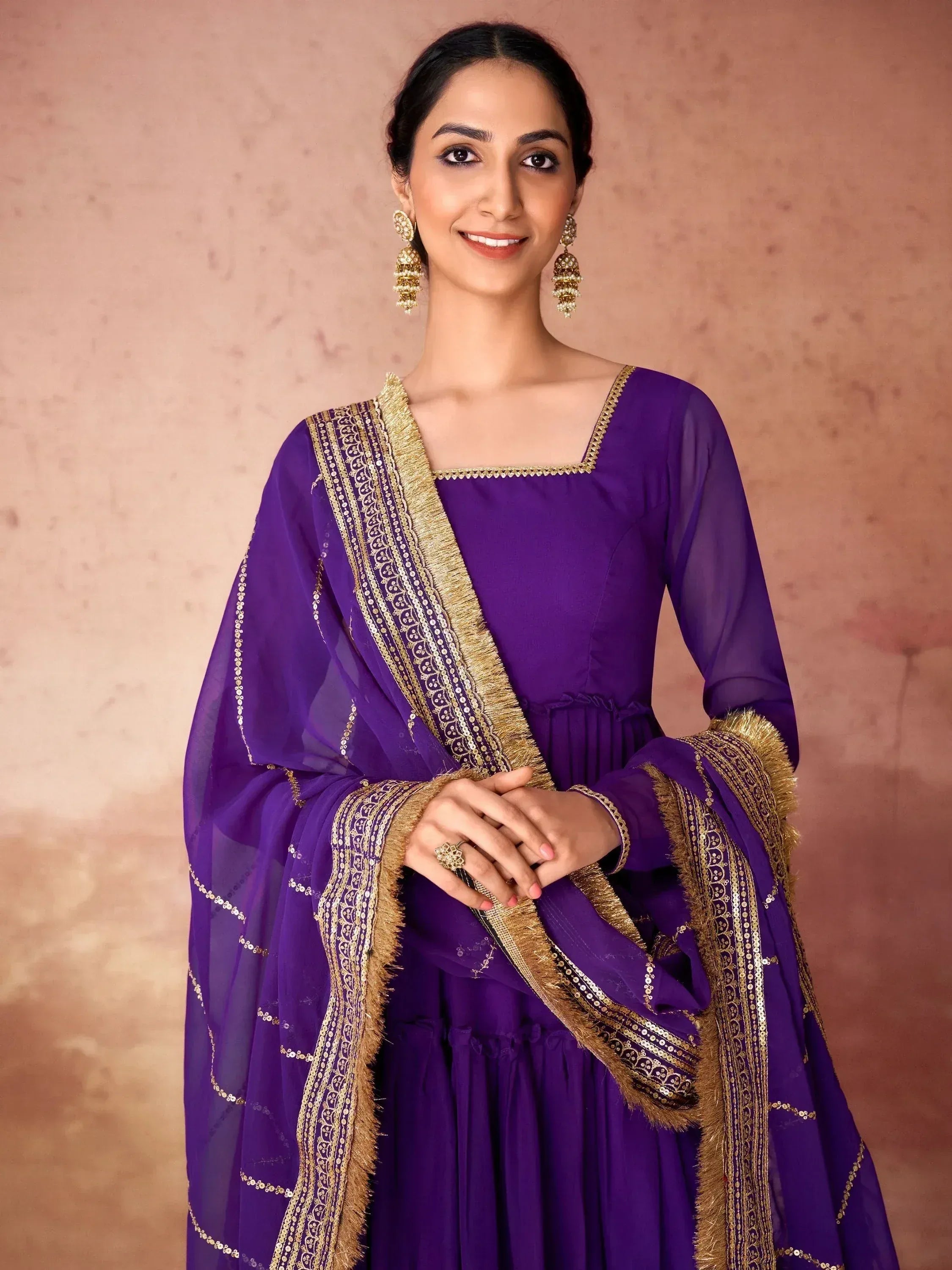 Woman in purple ethnic gown with gold trim and matching dupatta, festive Indian attire