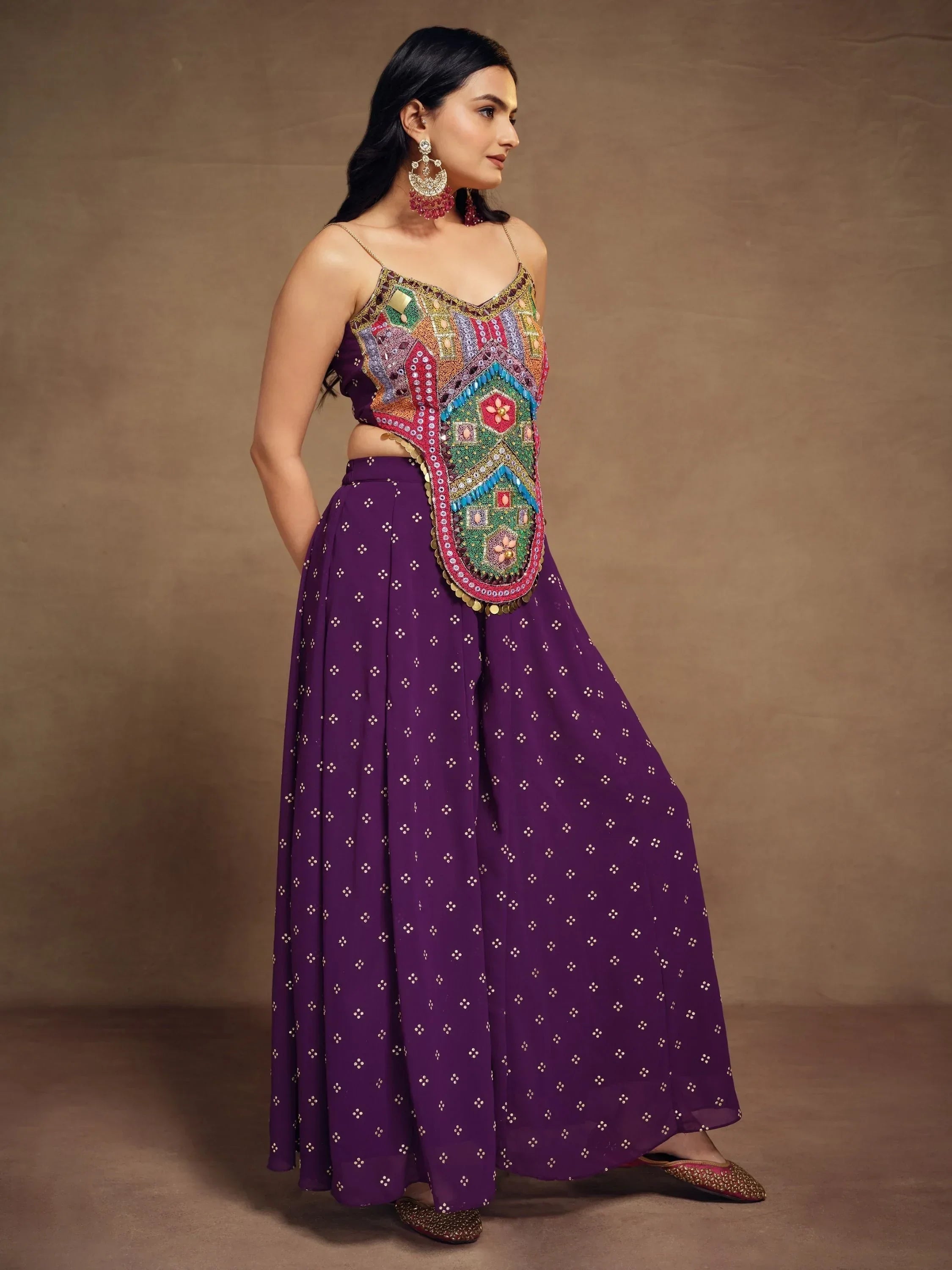 Woman wearing a purple ethnic lehenga with embroidered crop top and statement earrings