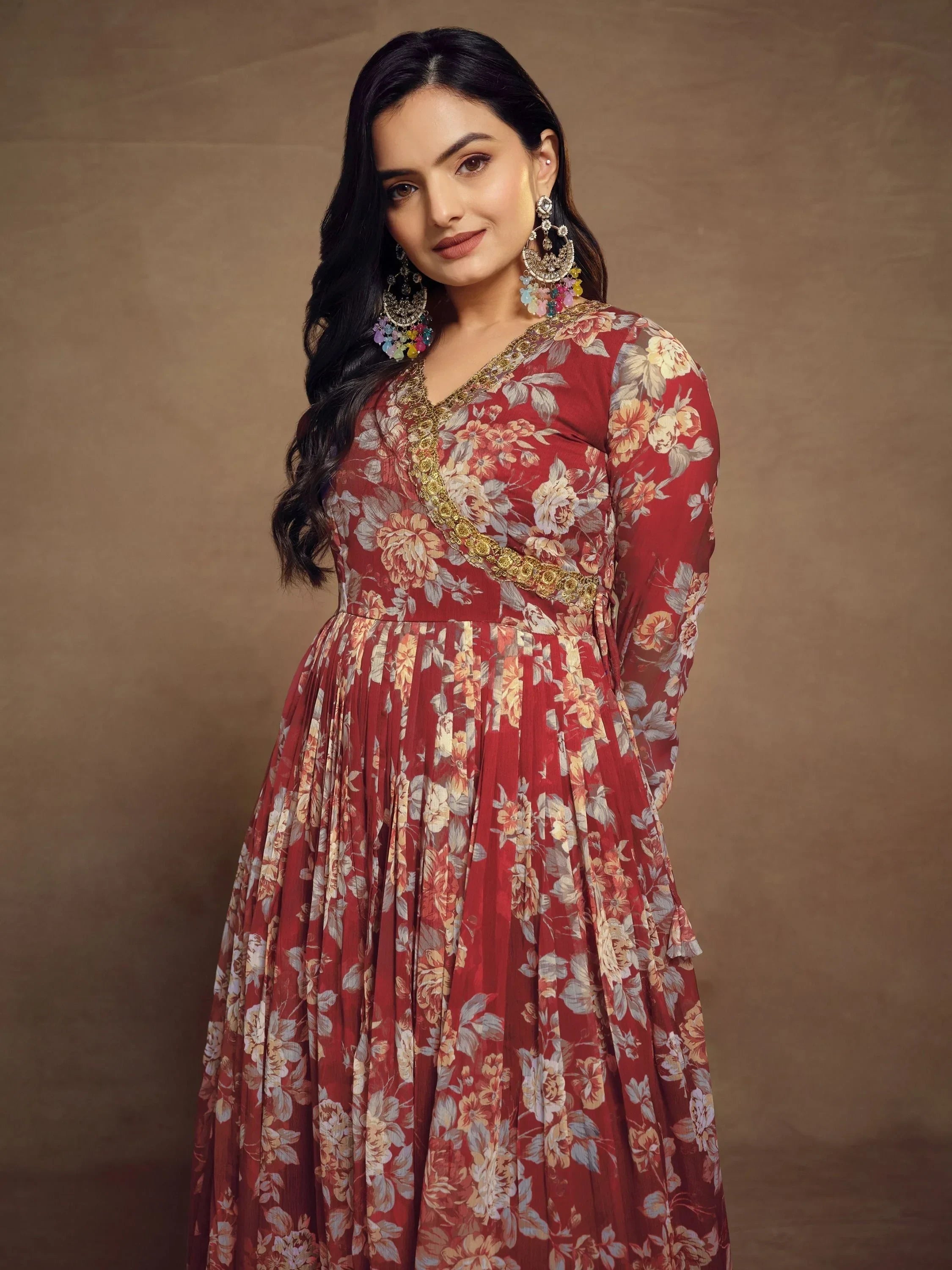Woman in a maroon floral ethnic gown with gold embroidery and statement earrings