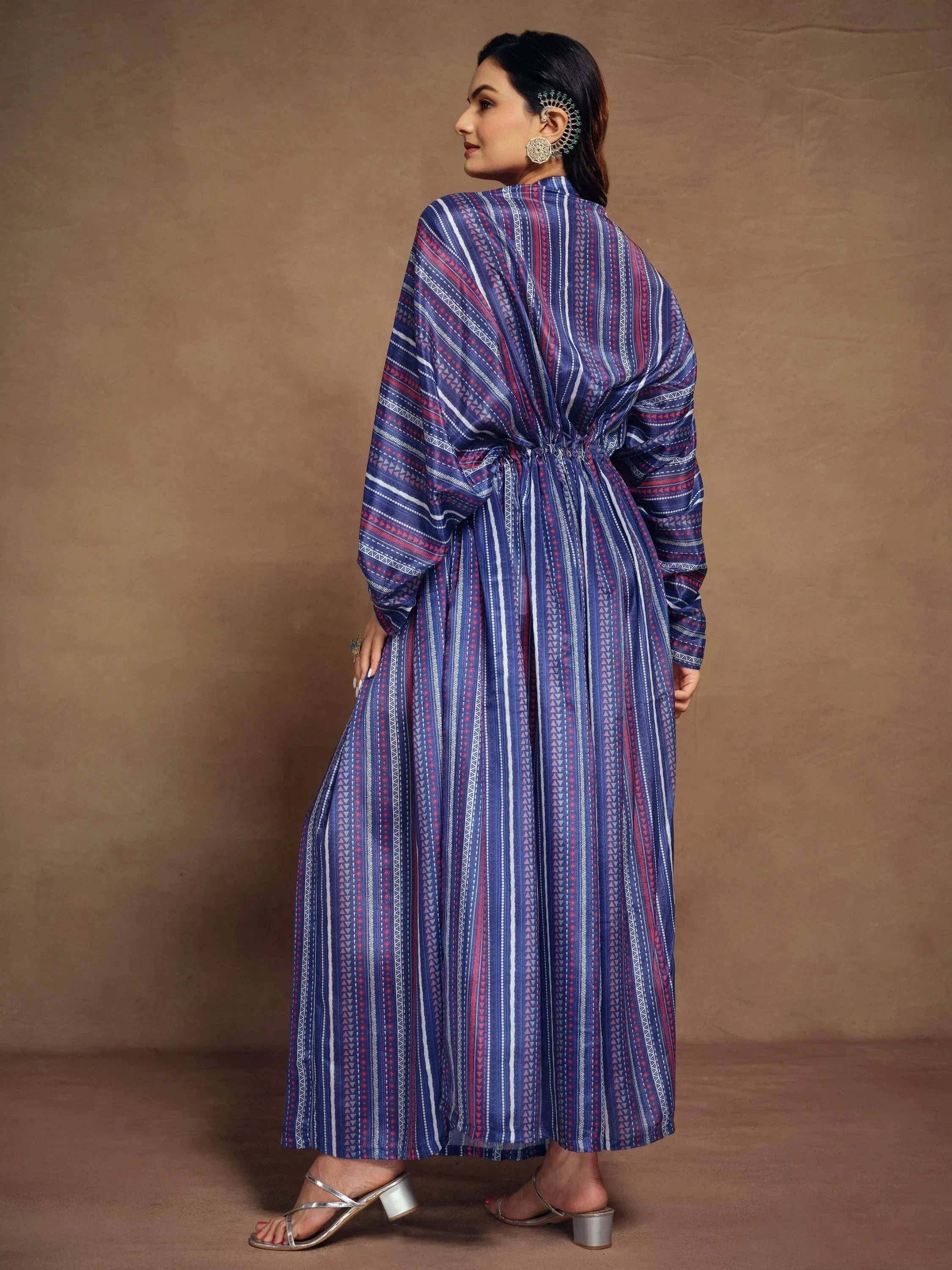 Woman in a colorful striped ethnic gown with long sleeves and metallic heels, back view