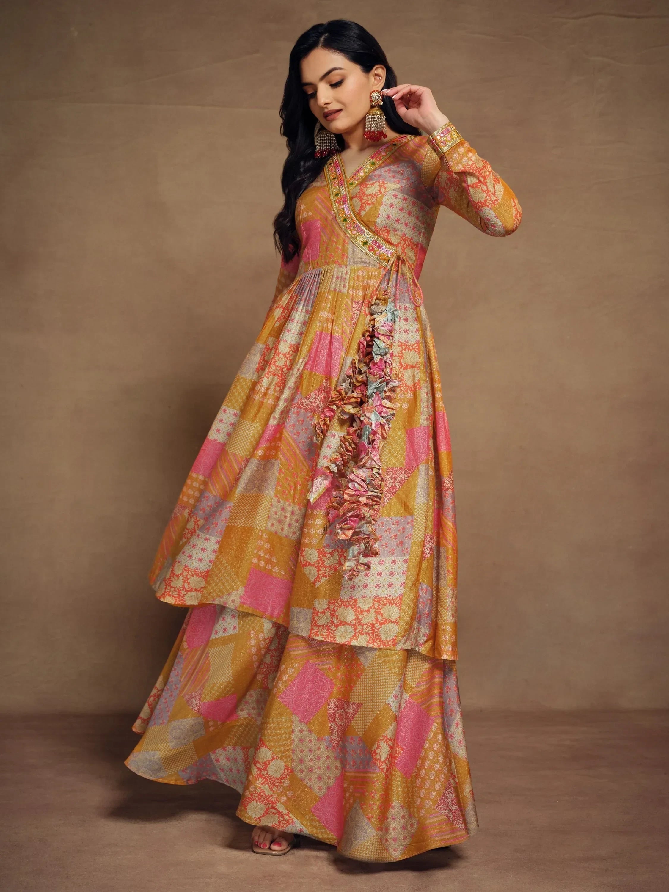 Woman wearing a patchwork multicolor printed ethnic gown with floral details and statement earrings