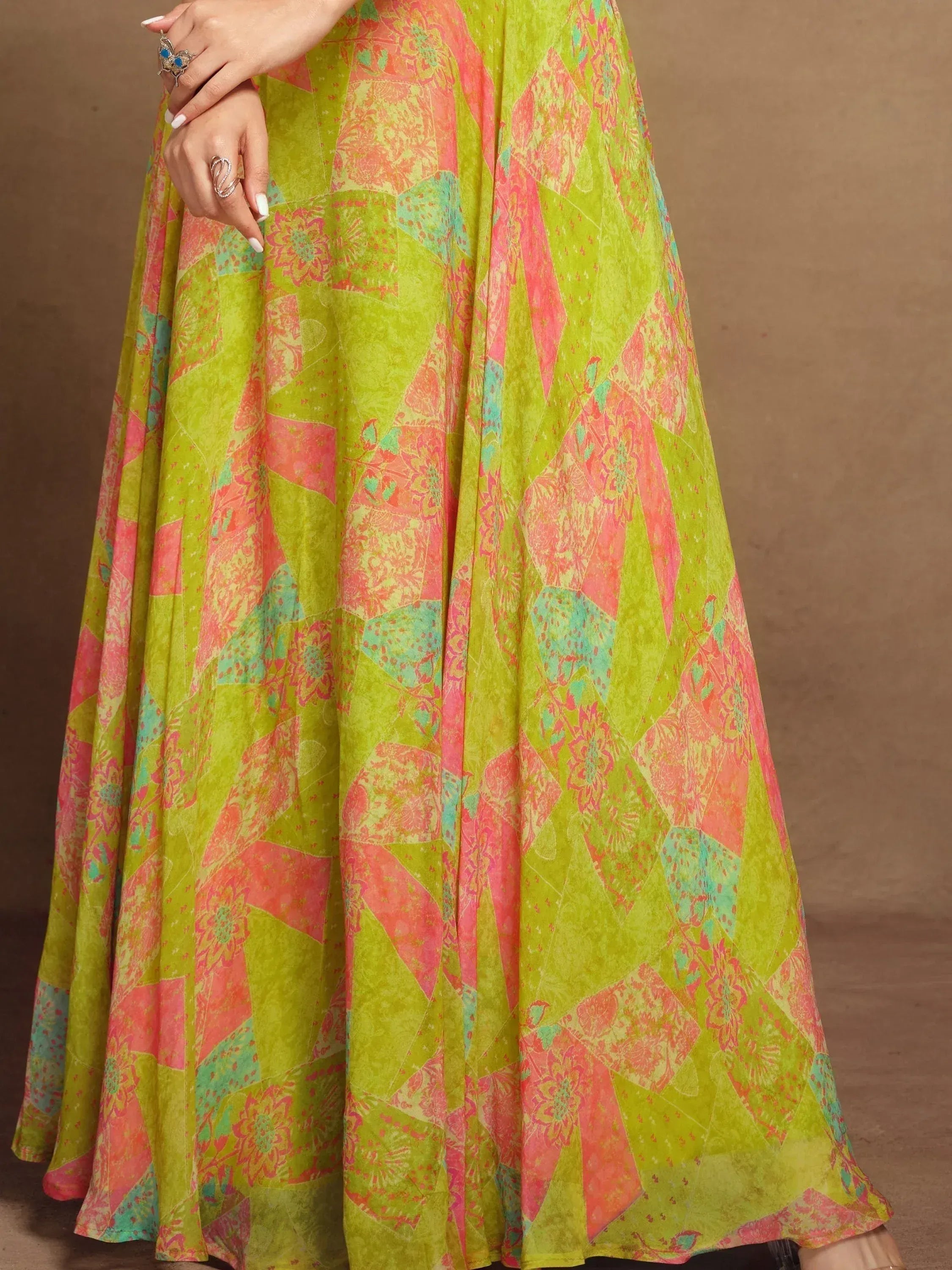 Vibrant green and pink printed ethnic gown with floral patchwork design, perfect for festive occasions.