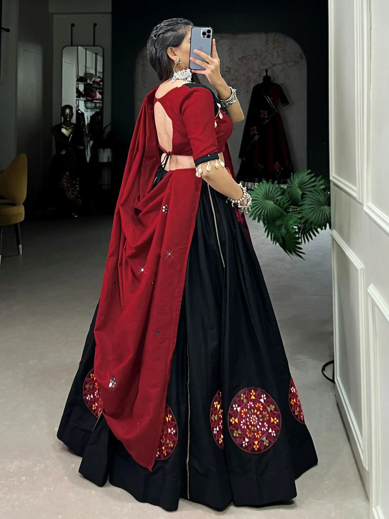 Woman in black and red ethnic lehenga choli with mirror work, taking mirror selfie in boutique