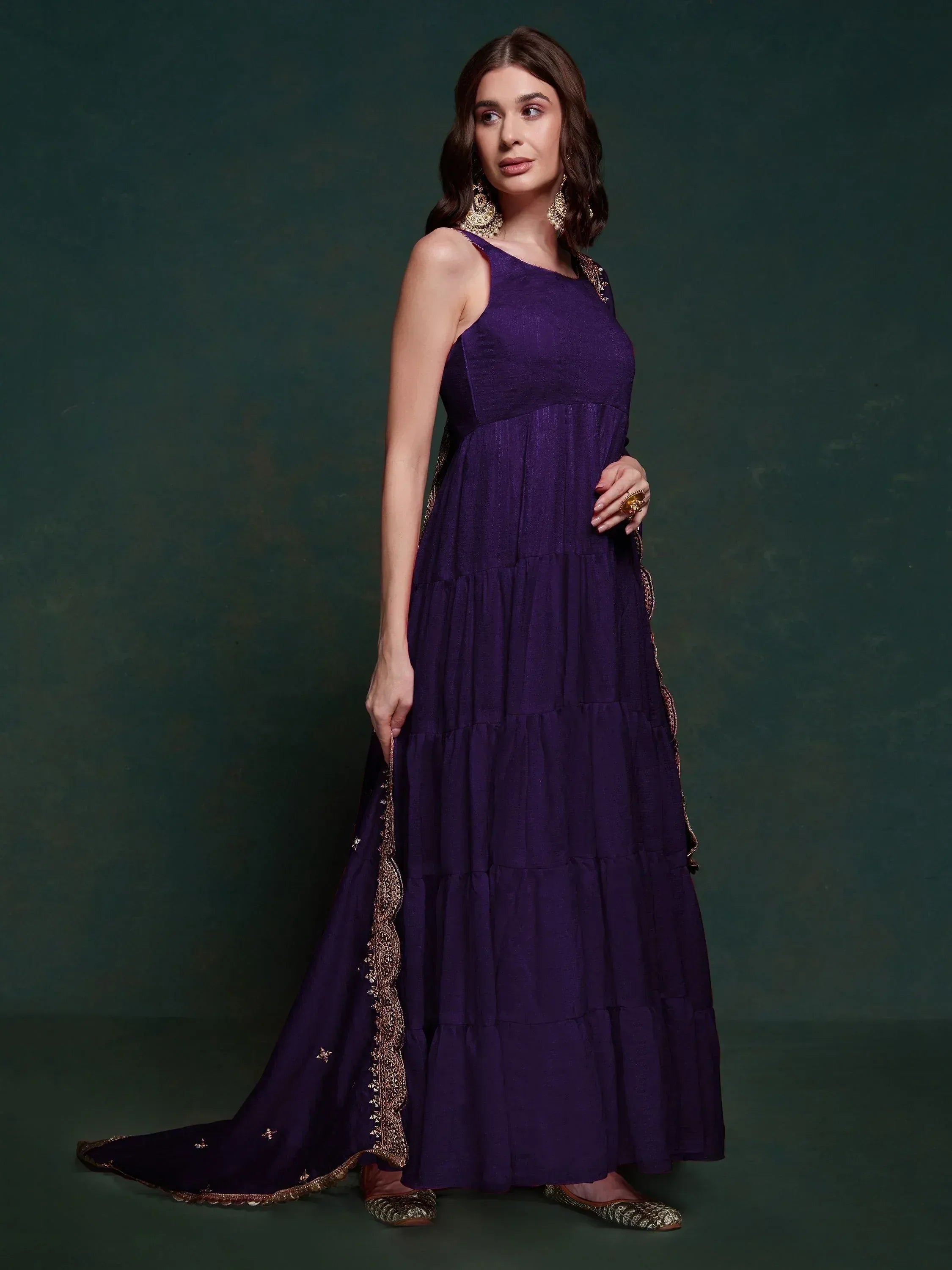 Purple ethnic gown with gold embroidery, tiered skirt, and matching dupatta for Indian occasions