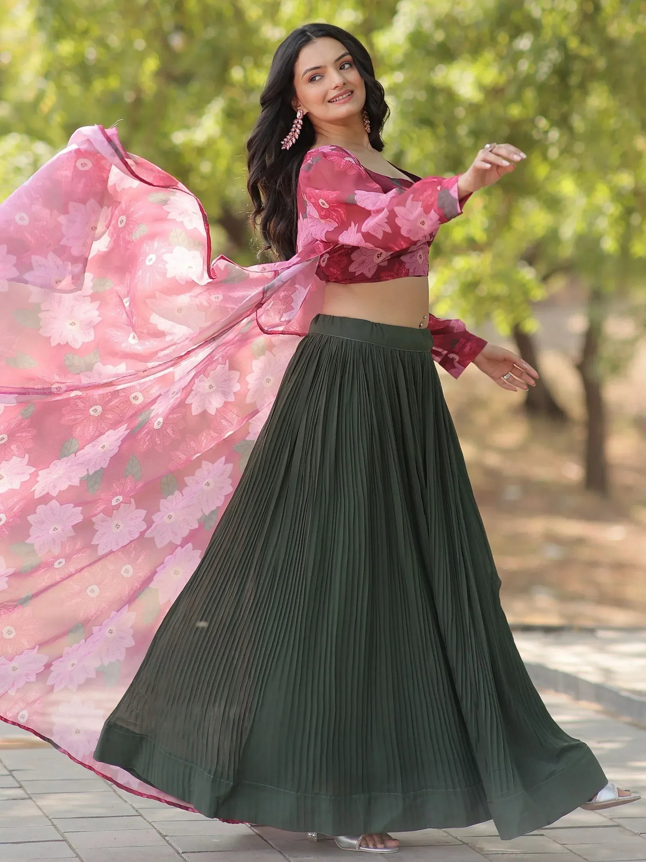 Woman in floral pink crop top with olive green pleated skirt, twirling outdoors