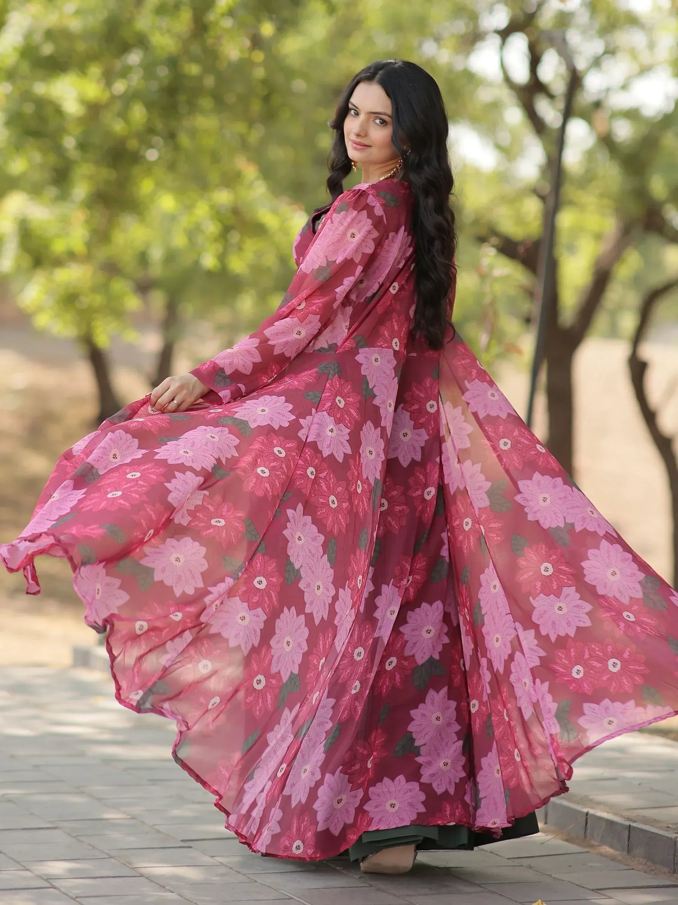 Woman in flowing pink floral ethnic gown, perfect for Indian occasions and festive wear.