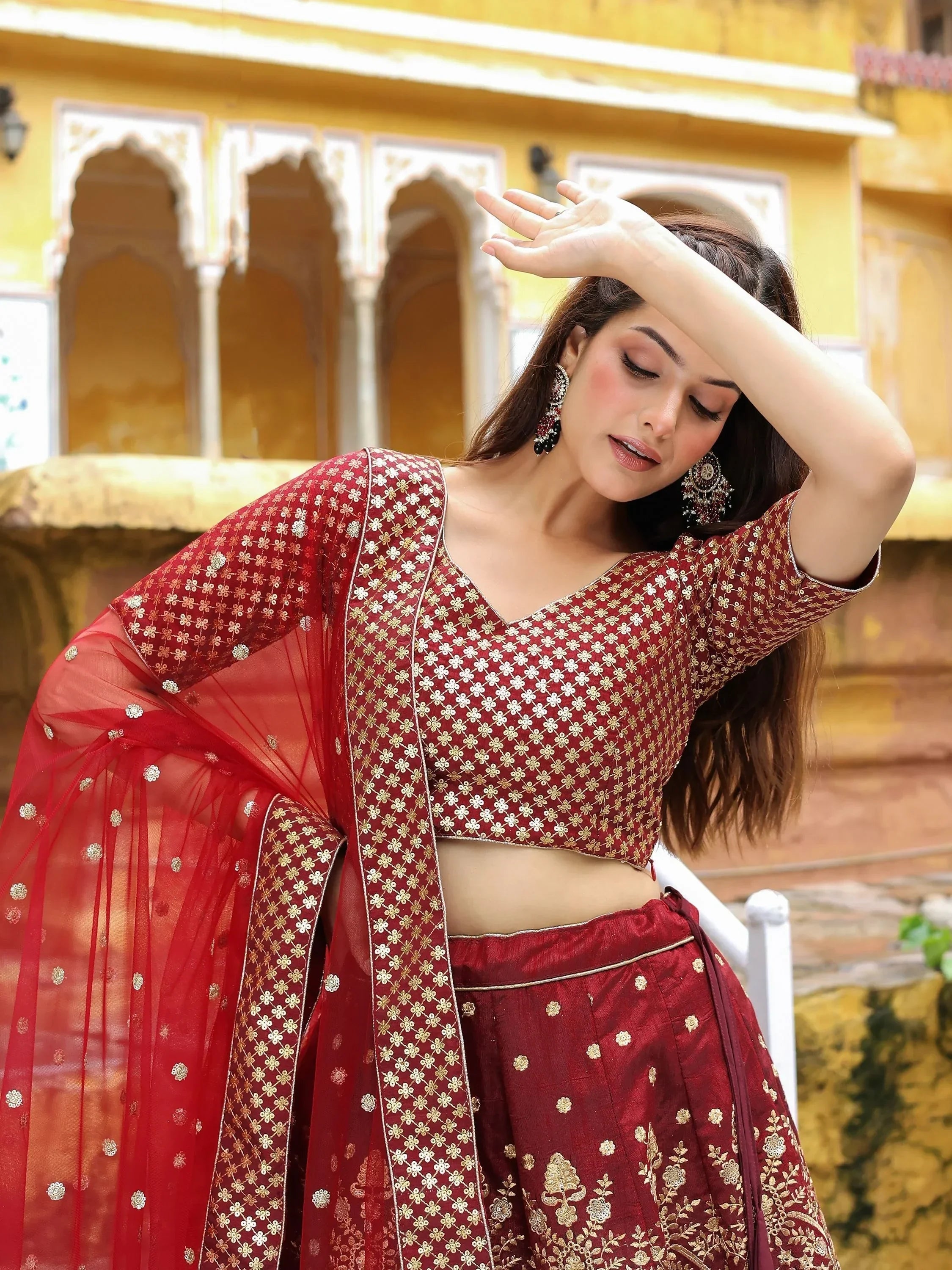 Woman in maroon embroidered lehenga choli with sheer dupatta, traditional Indian ethnic wear