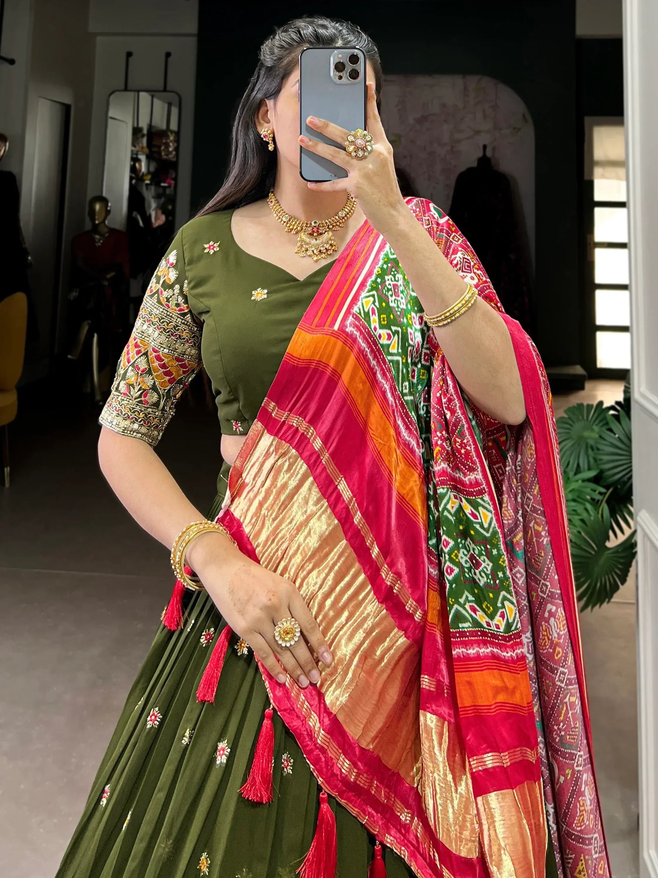Woman in olive green embroidered lehenga choli with colorful printed dupatta, traditional Indian ethnic wear