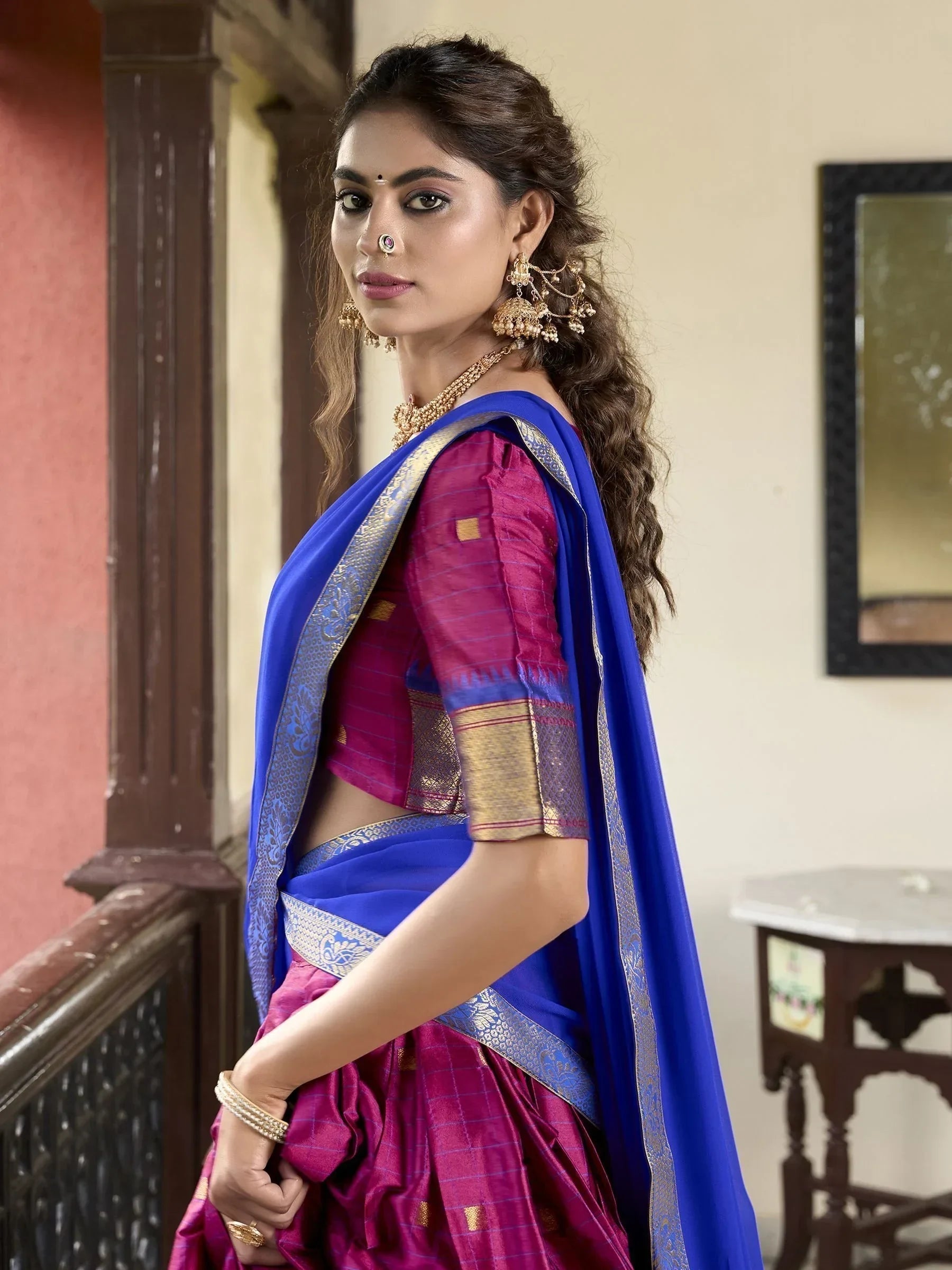 Woman in vibrant purple and blue ethnic saree with gold border, traditional Indian wear