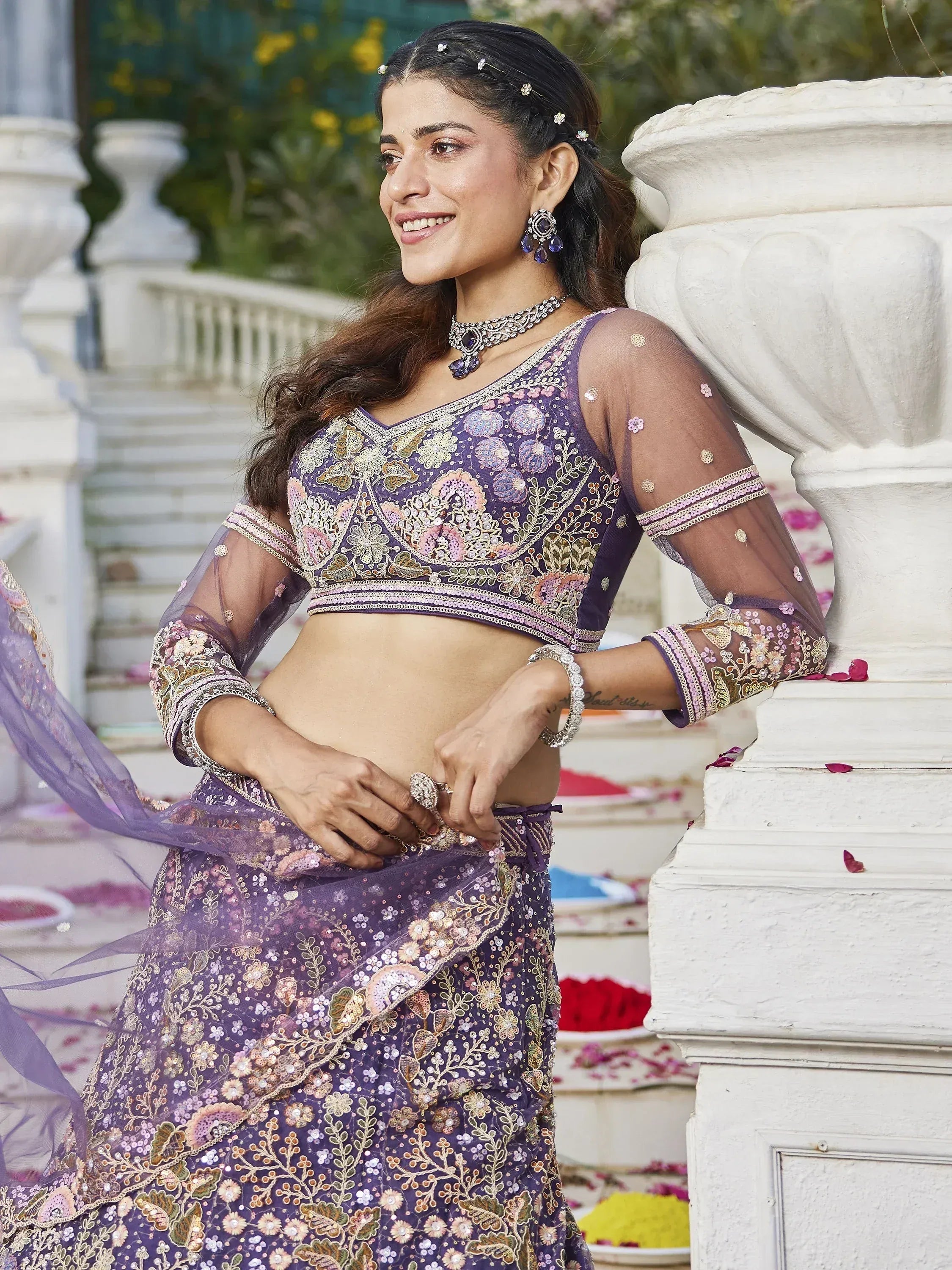 Purple embroidered lehenga choli with floral motifs, sheer sleeves, and traditional jewelry for Indian ethnic wear