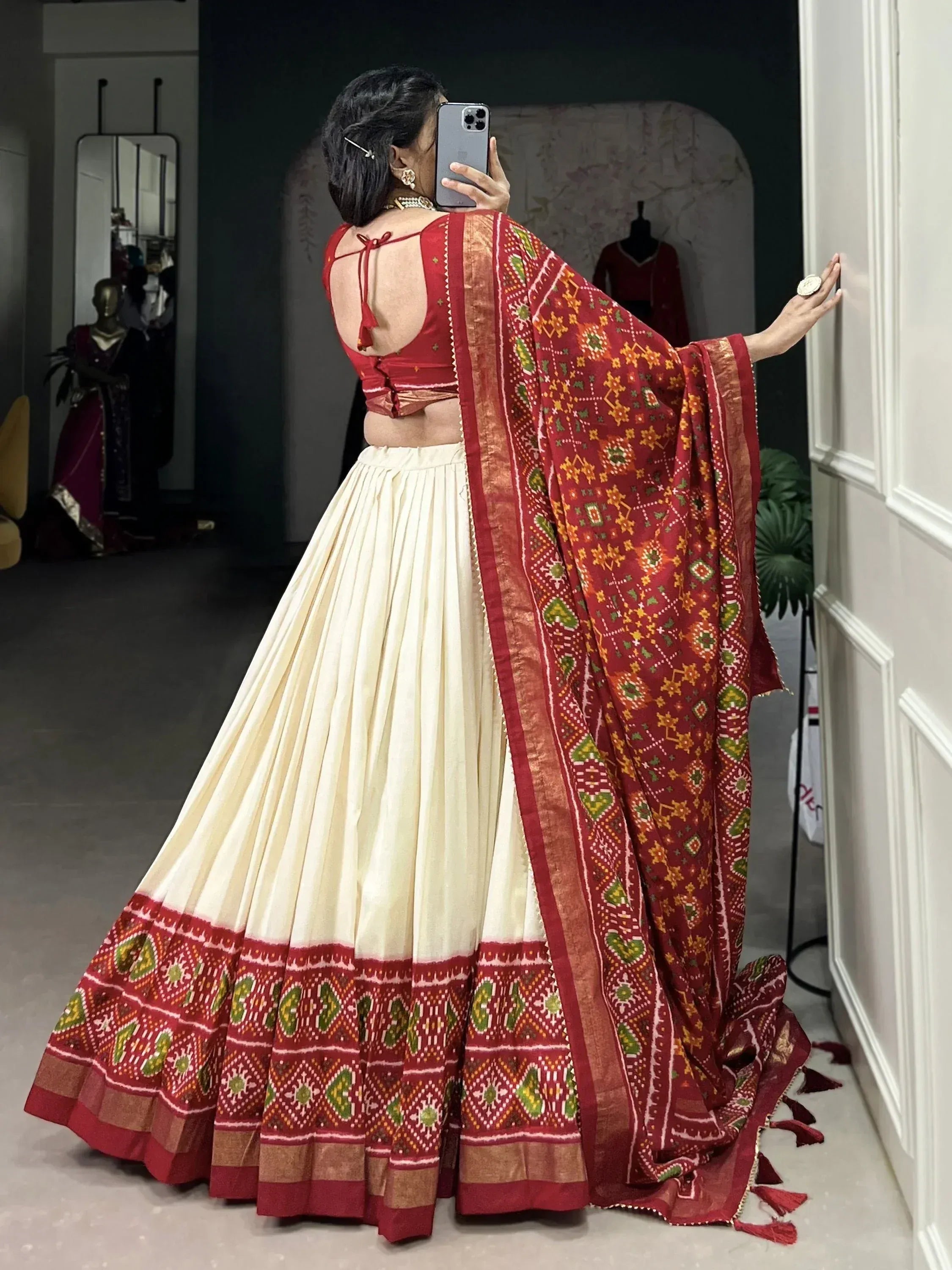 Red and cream ethnic lehenga choli with printed dupatta, back view in boutique