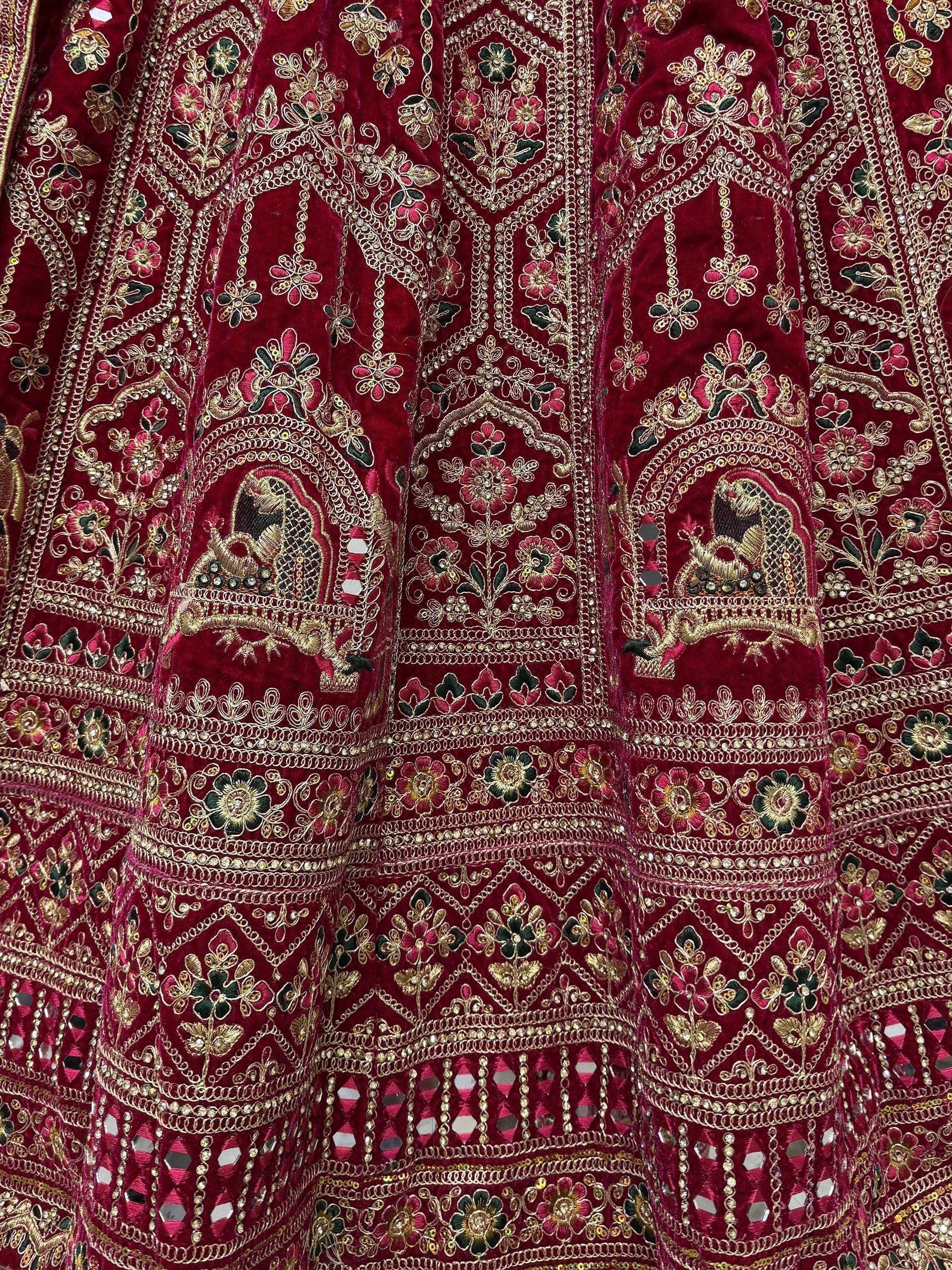 Rich maroon velvet lehenga with intricate gold embroidery, floral motifs, and mirror work for Indian ethnic wear.