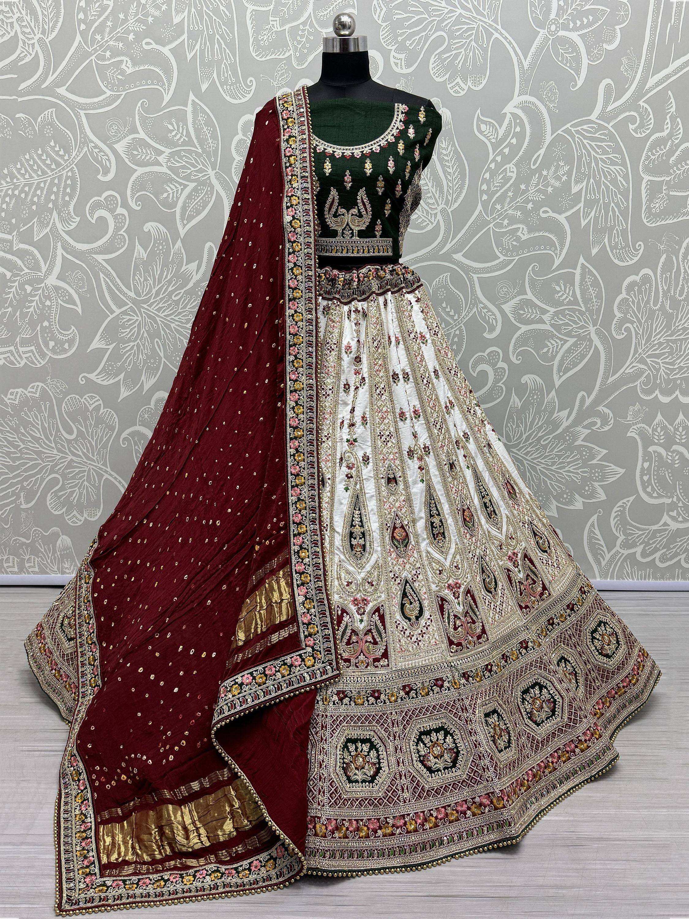 Designer lehenga choli with green blouse, white skirt, and maroon dupatta, featuring intricate embroidery and floral patterns.