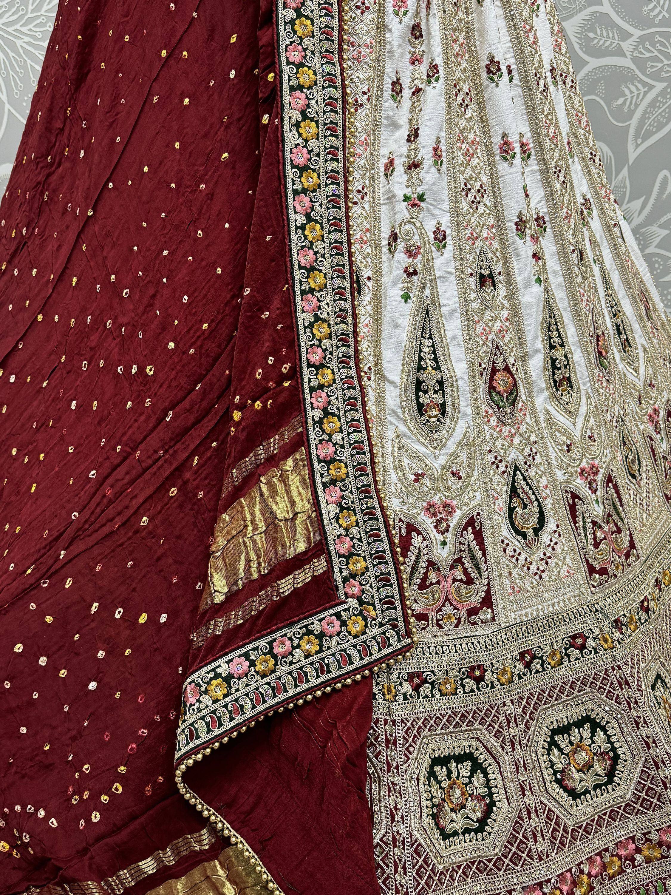 White and maroon embroidered lehenga choli with floral and paisley motifs, perfect for Indian ethnic wear.