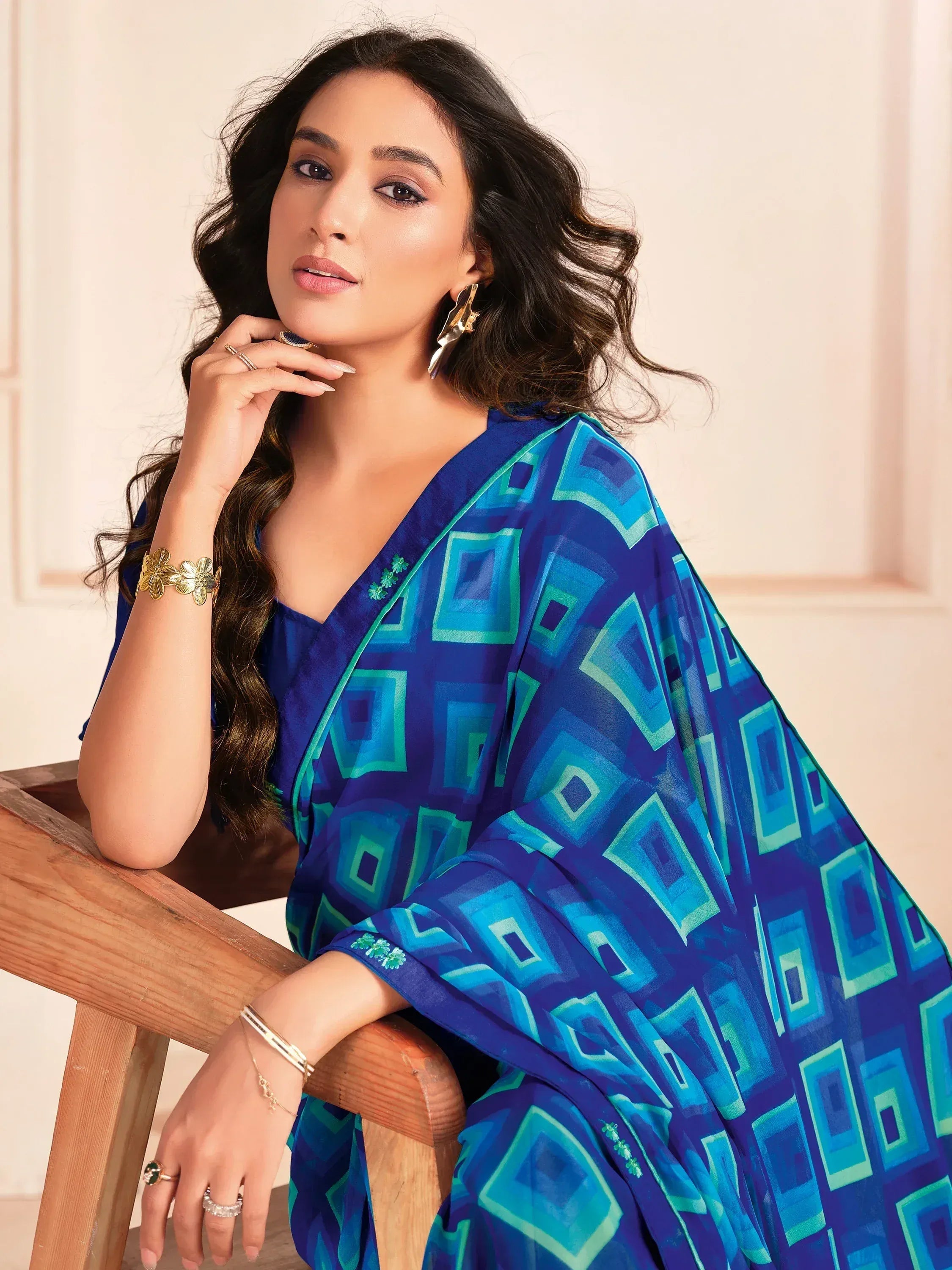 Woman in blue geometric print ethnic gown with gold jewelry, styled for Indian fashion