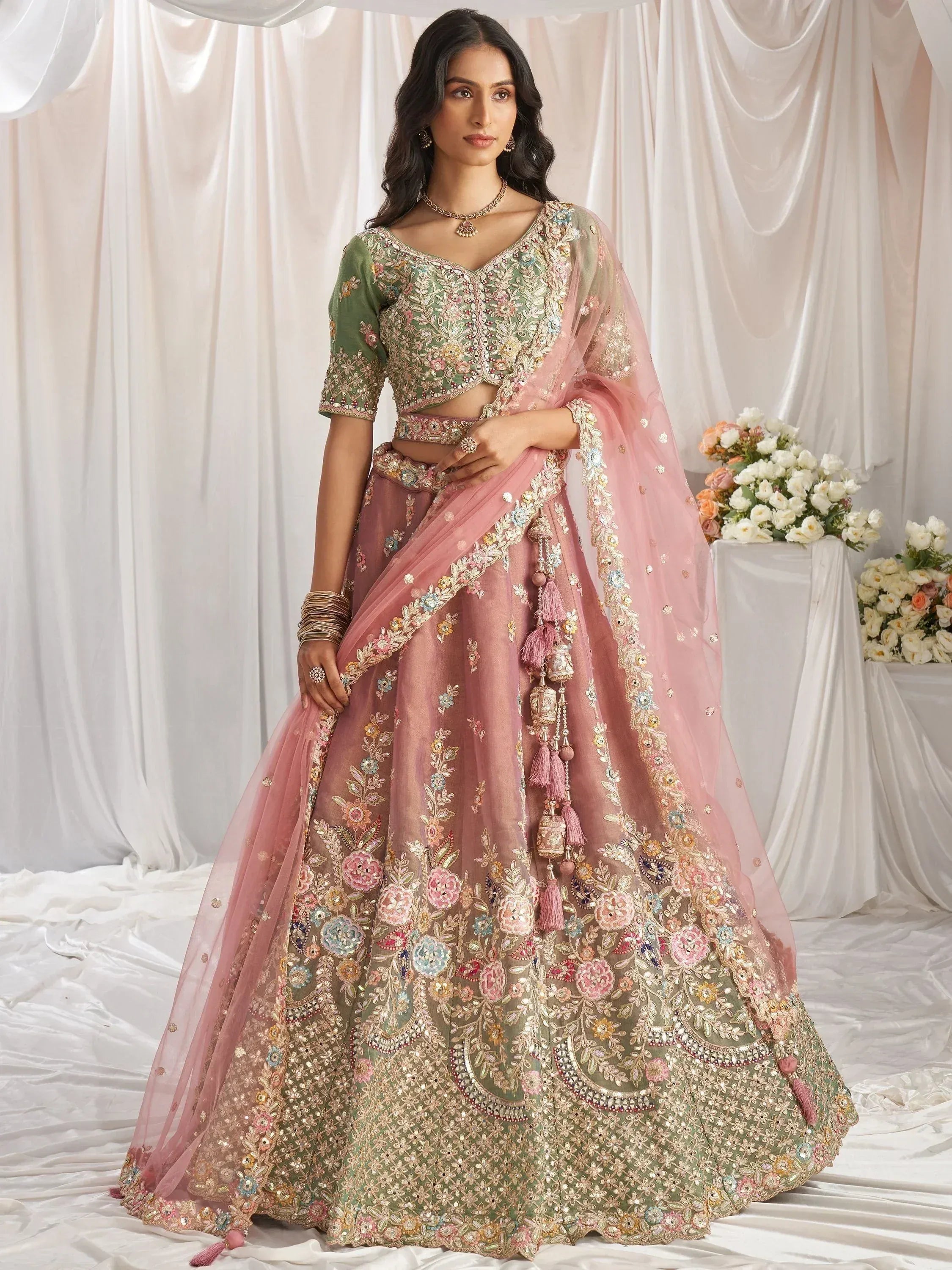 Designer lehenga choli with floral embroidery, pink dupatta, and tassels for Indian weddings