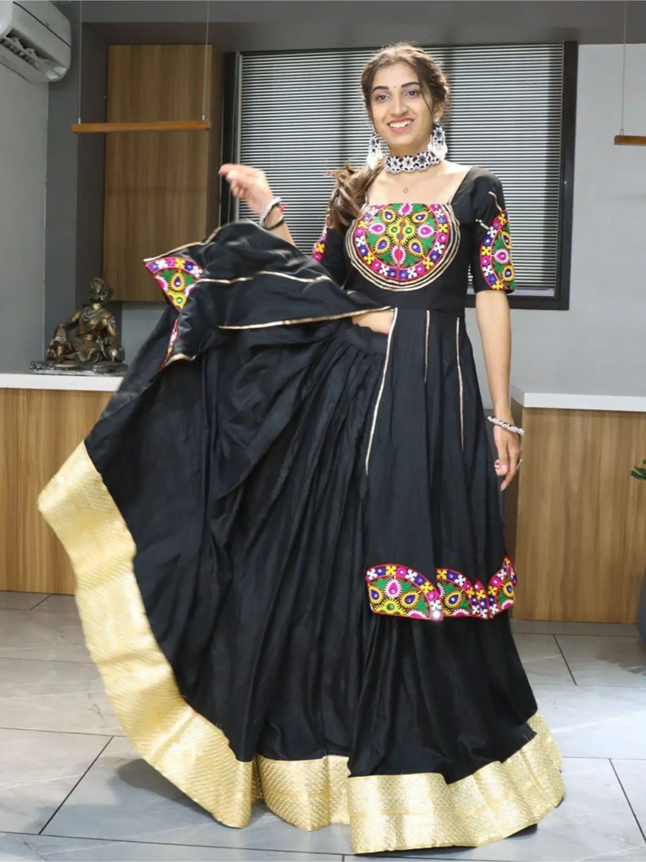 Black ethnic gown with colorful mirror work and gold border, perfect for Indian festive occasions