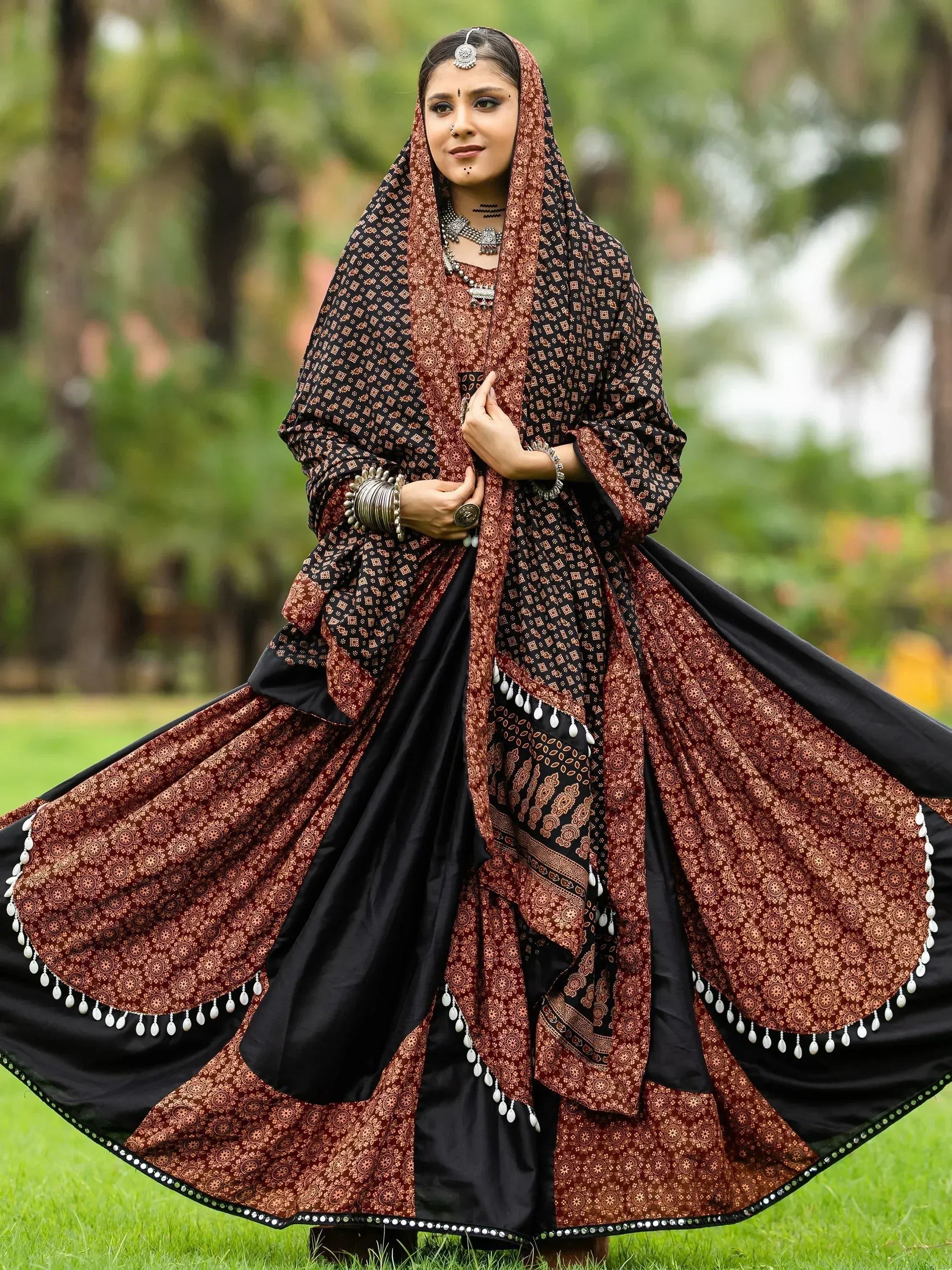 Woman in traditional Indian ethnic wear, maroon and black printed lehenga choli with dupatta, perfect for festive occasions.