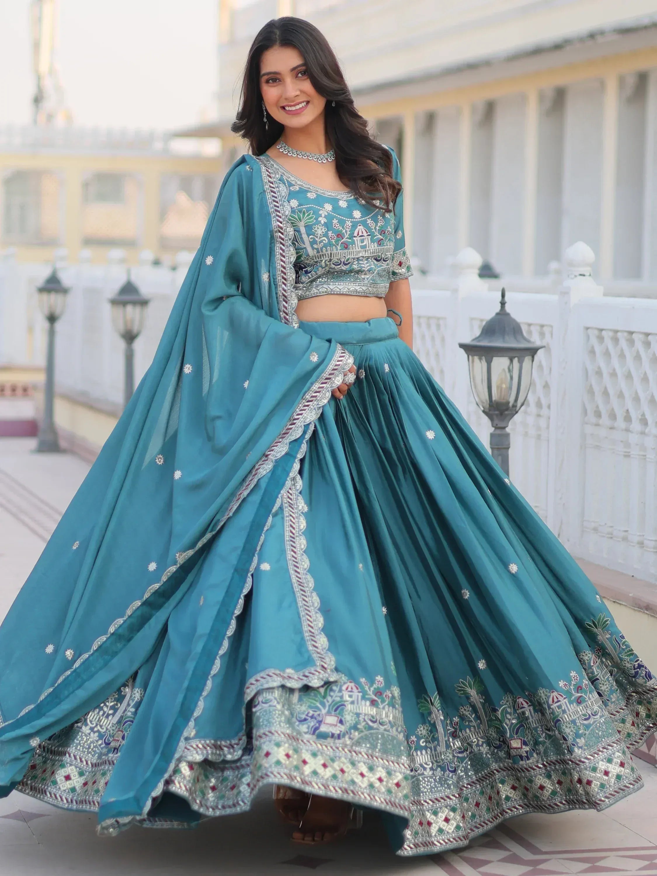 Teal designer lehenga choli with intricate embroidery and mirror work, perfect for Indian ethnic occasions.