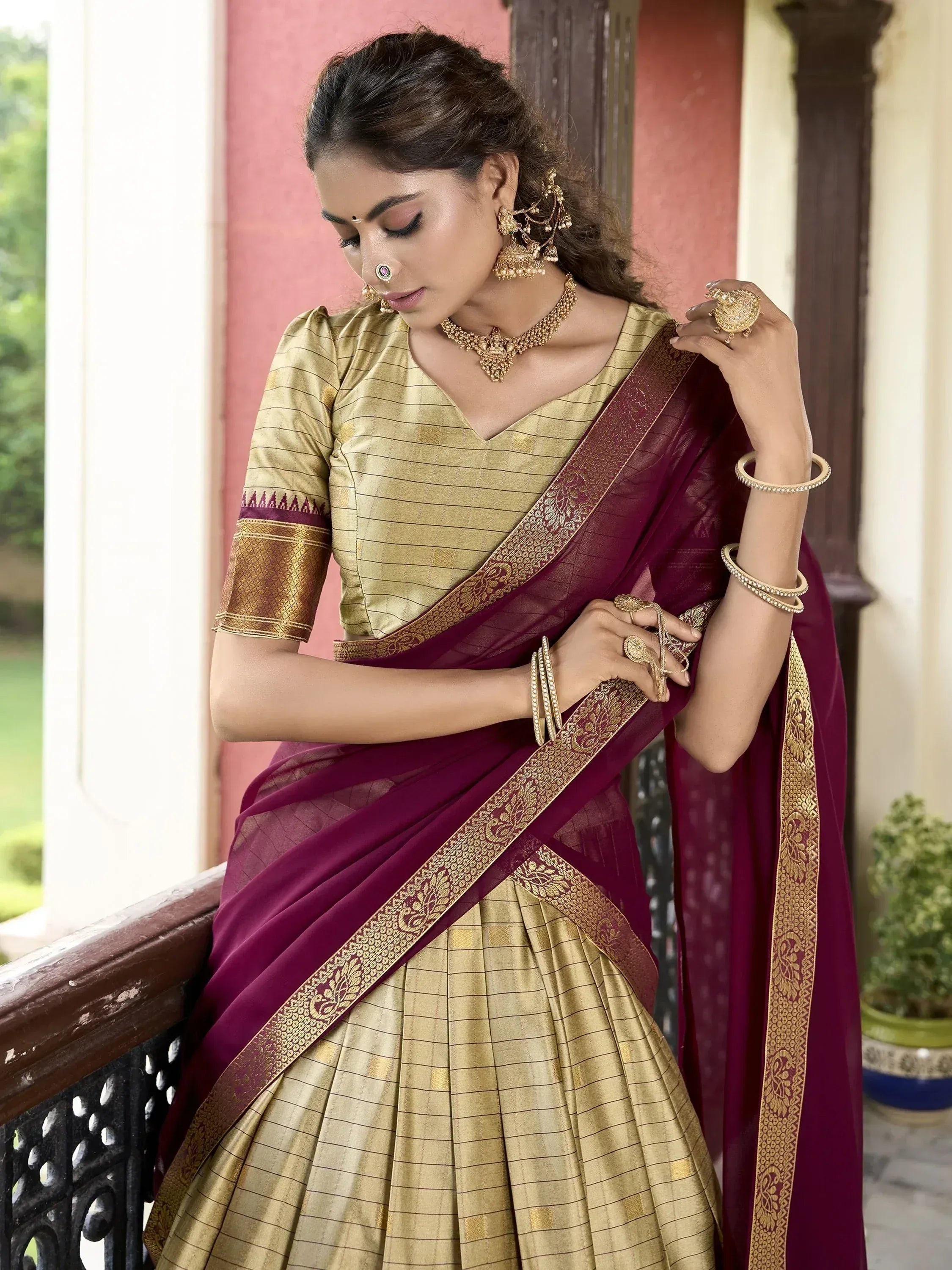 Elegant maroon and gold saree with intricate border, paired with designer blouse and traditional jewelry