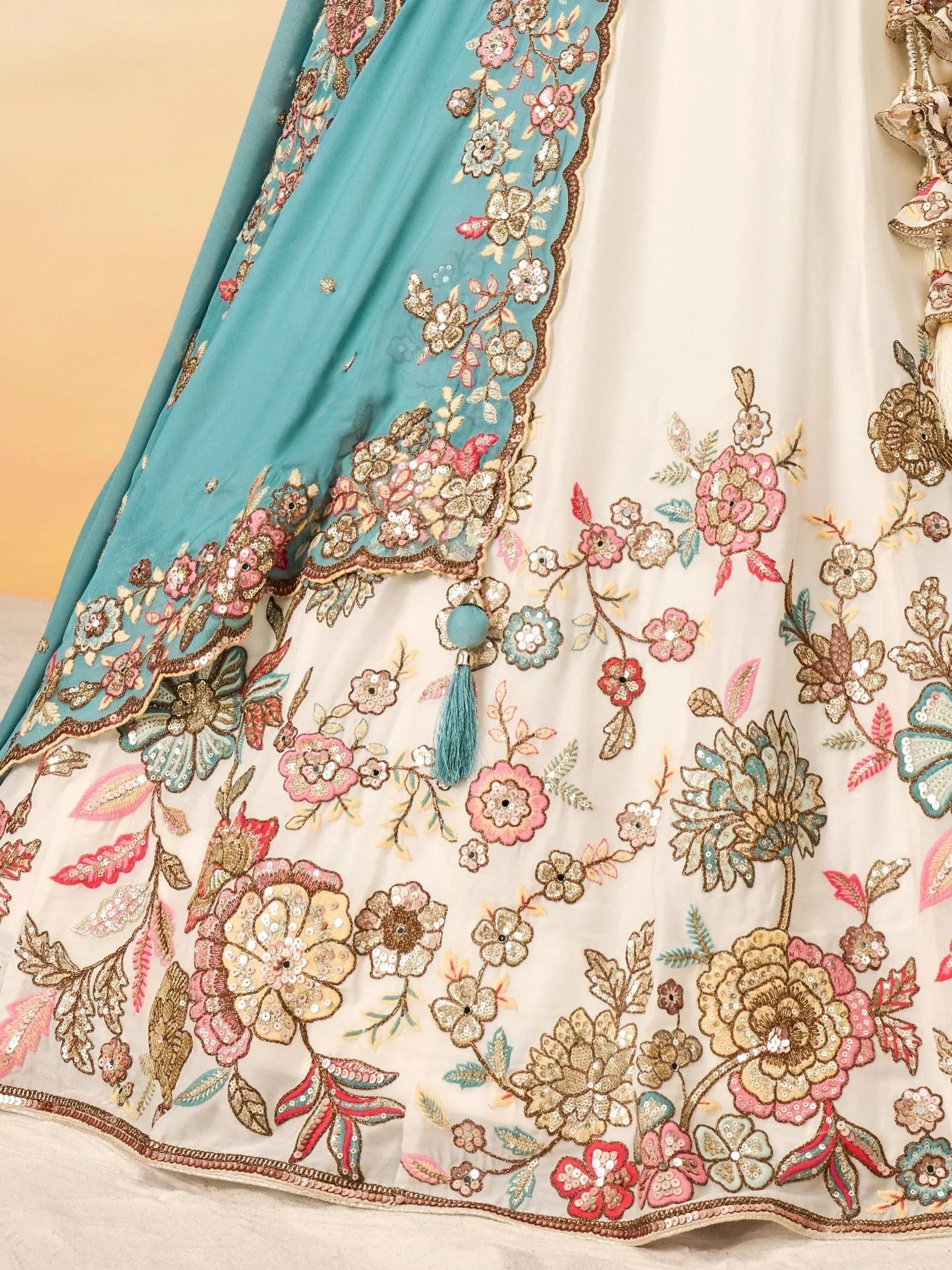 Floral embroidered Indian ethnic wear with sequins and tassels, featuring teal and cream colors.