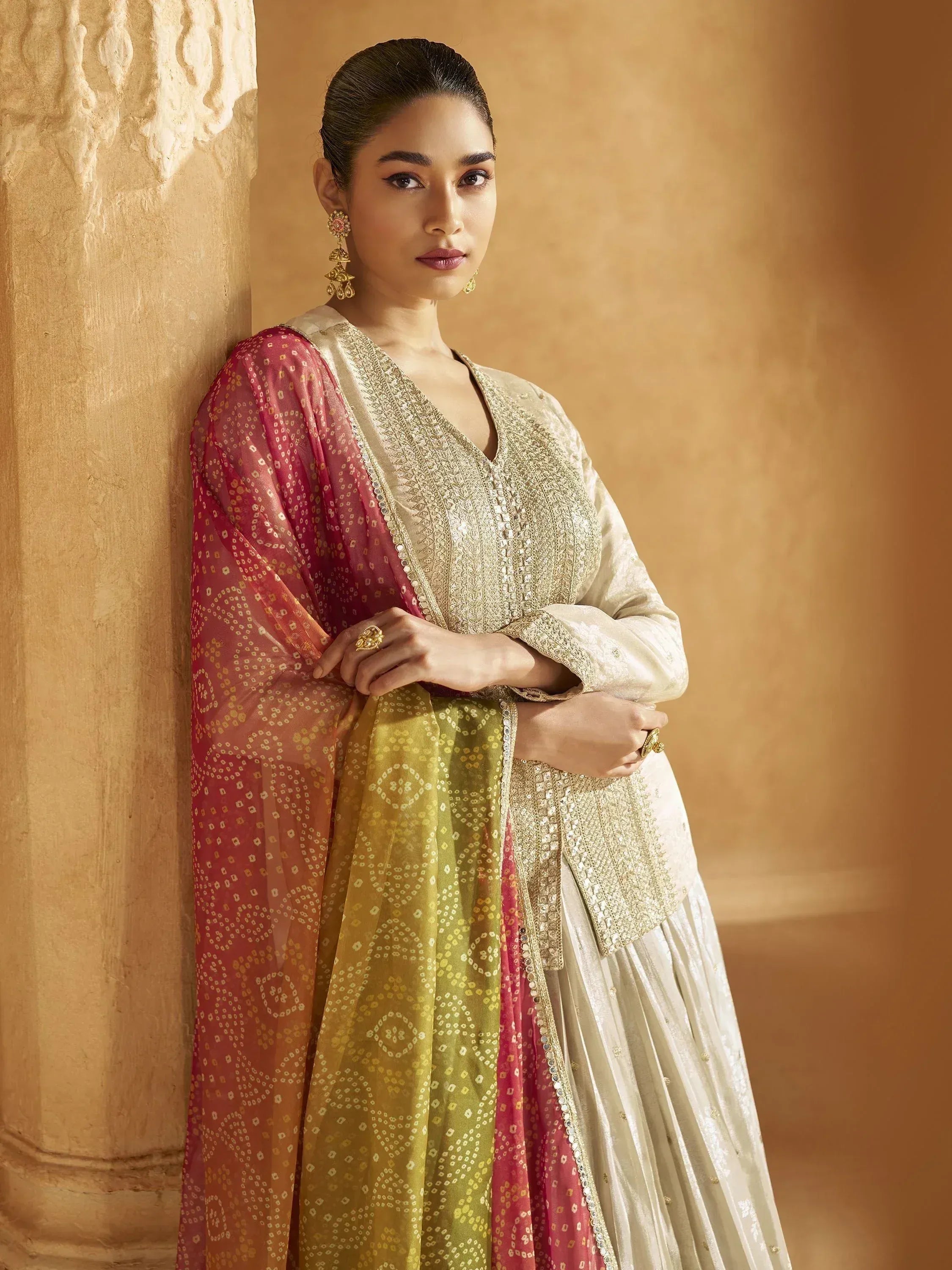 Elegant Indian ethnic wear with embroidered cream kurta, pleated skirt, and colorful dupatta for festive occasions