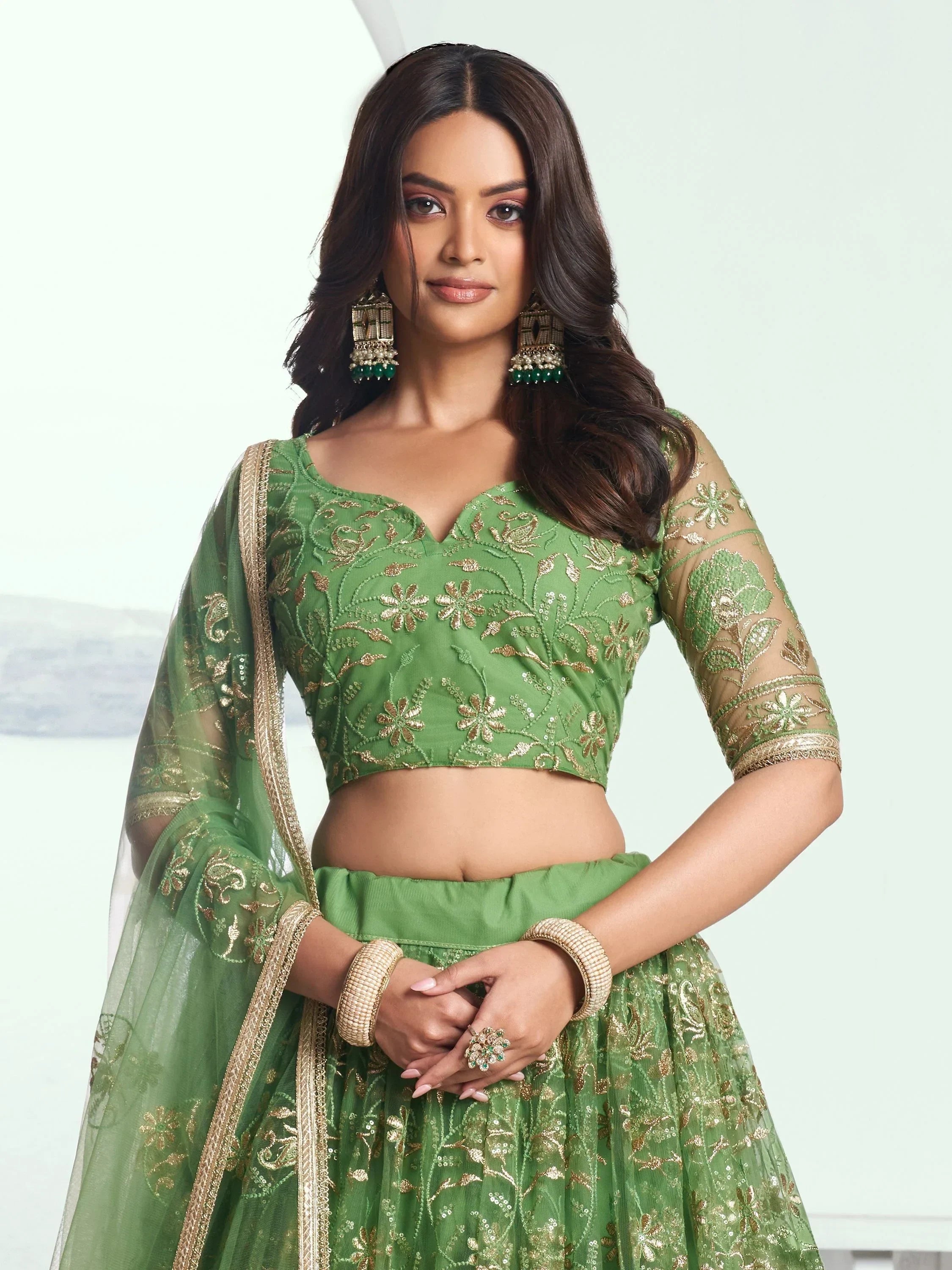 Green embroidered lehenga choli with gold floral work, sheer sleeves, and matching dupatta for Indian ethnic wear