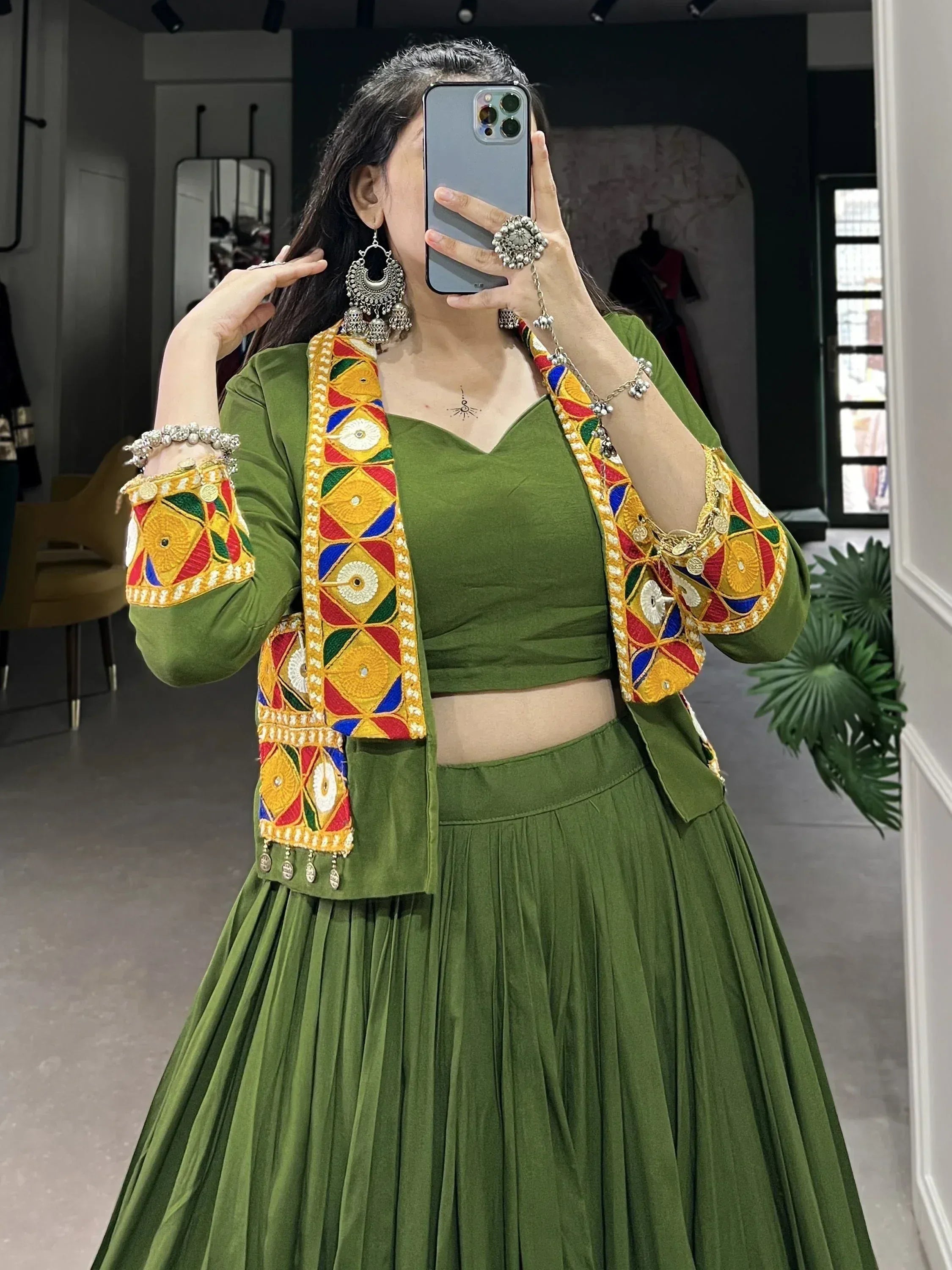 Green embroidered lehenga choli with colorful mirror work and traditional jewelry