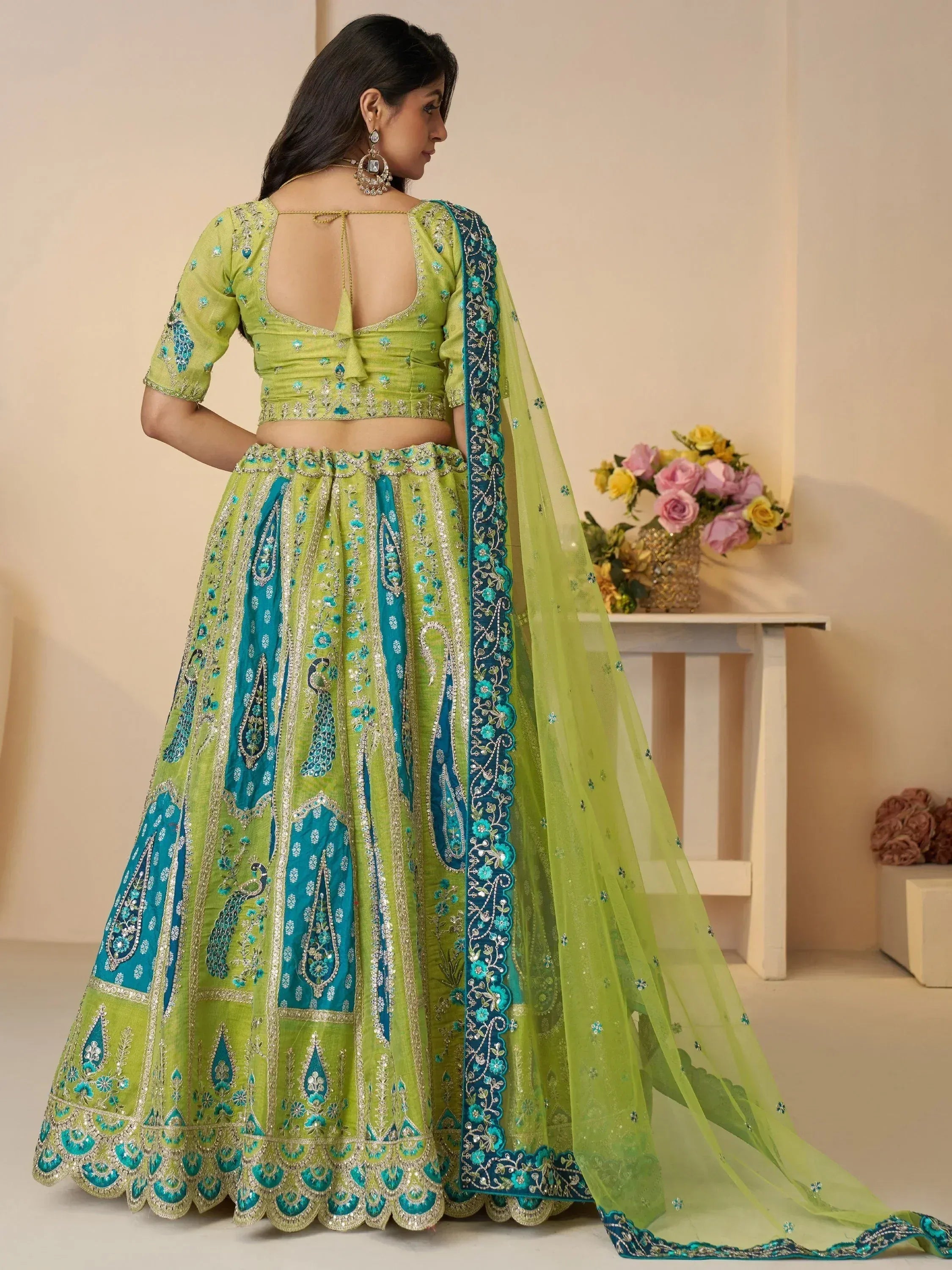 Green and teal embroidered lehenga choli with peacock motifs and sheer dupatta, perfect for Indian ethnic occasions.
