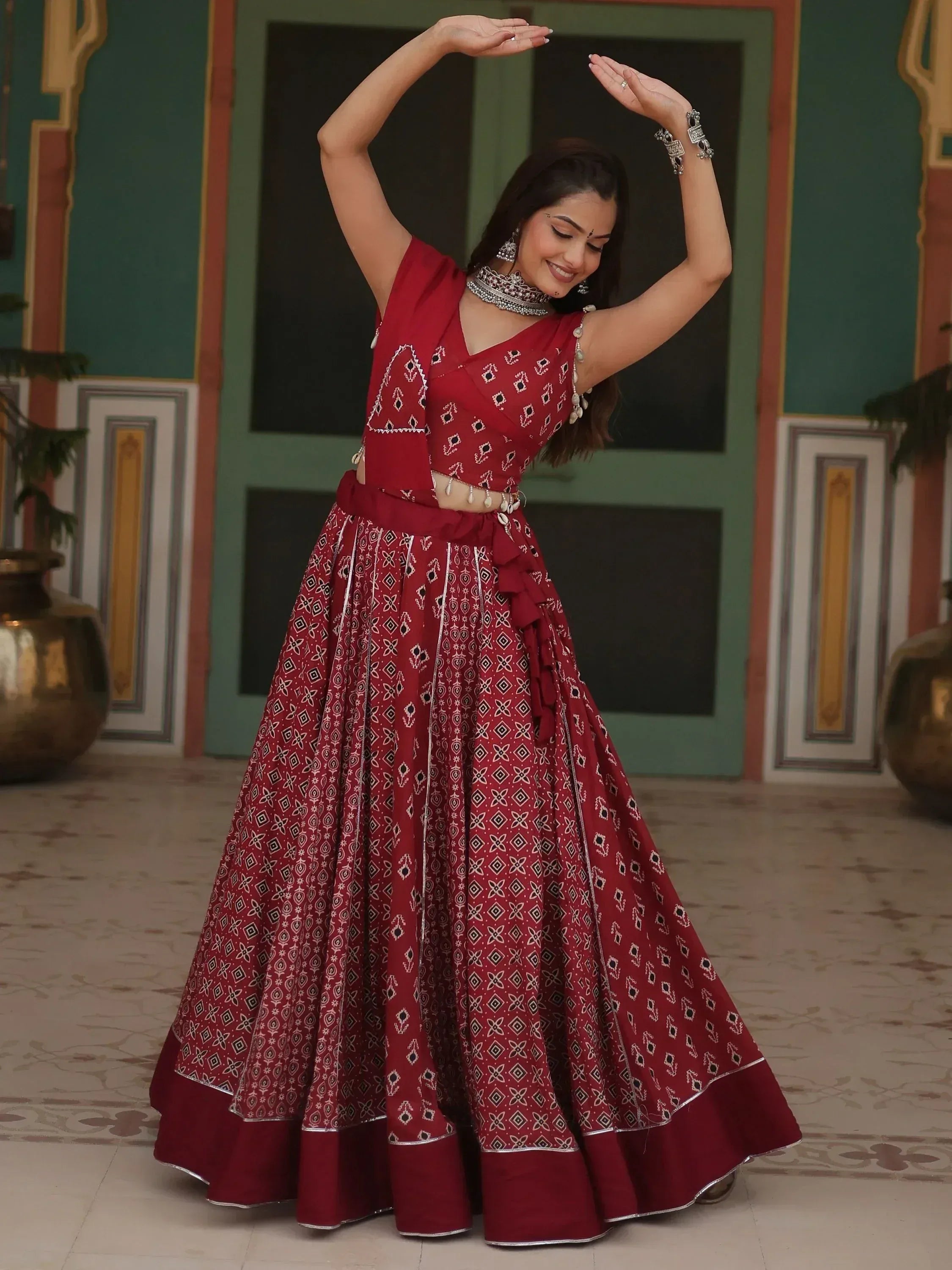 Woman in red printed lehenga choli with silver jewelry, dancing in traditional Indian attire