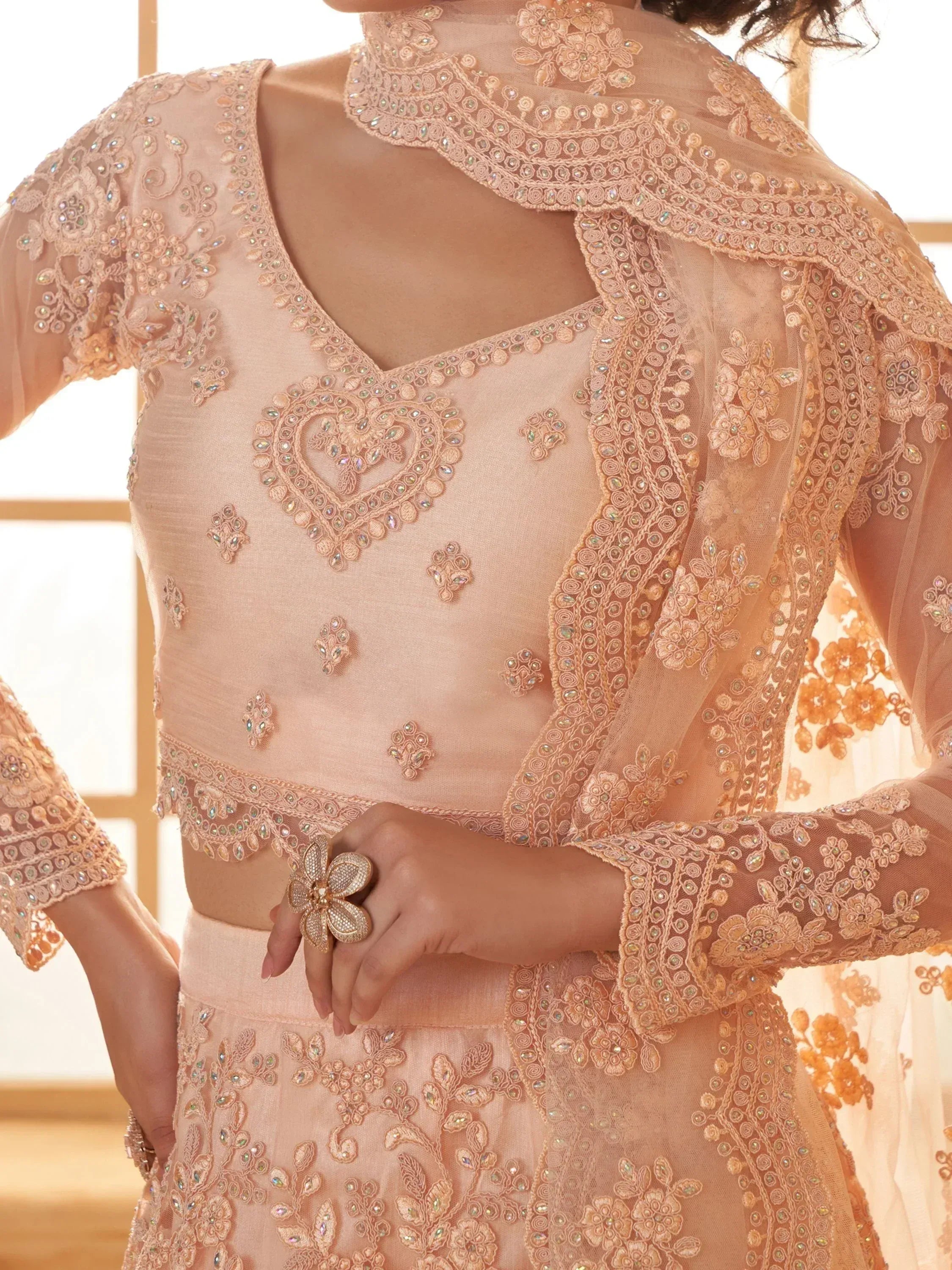 Peach embroidered lehenga choli with floral lace and heart motif, perfect for Indian ethnic wear occasions.