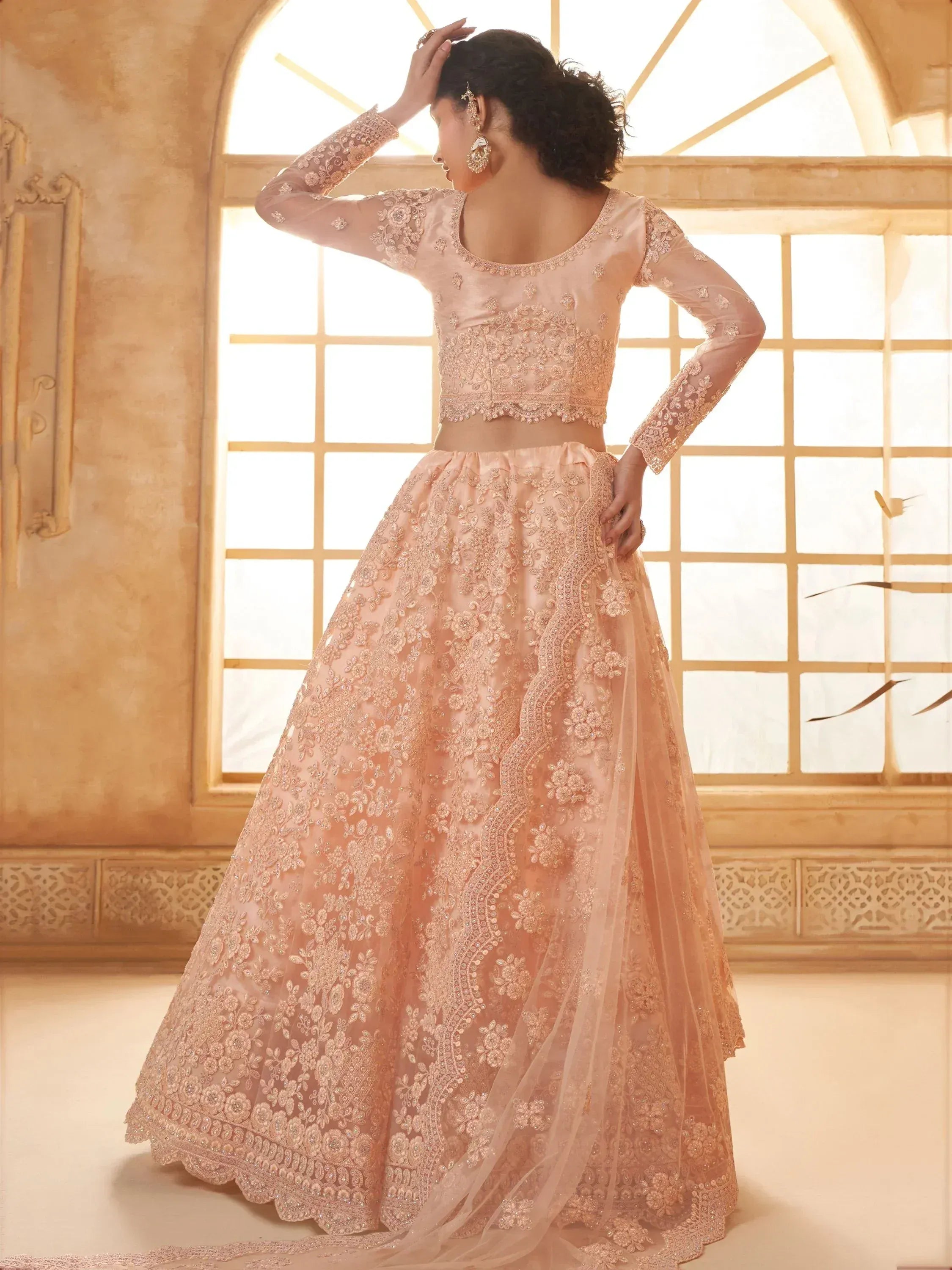 Elegant peach lehenga choli with intricate floral embroidery and sheer sleeves, perfect for Indian ethnic wear.