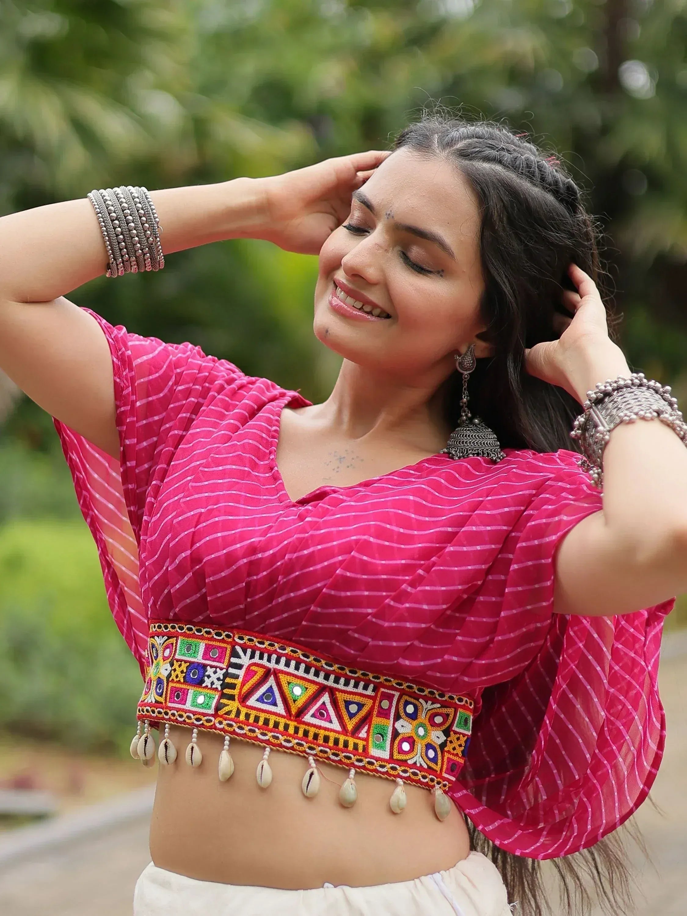 Pink ethnic crop top with mirror work and shell tassels, paired with white bottoms and silver jewelry