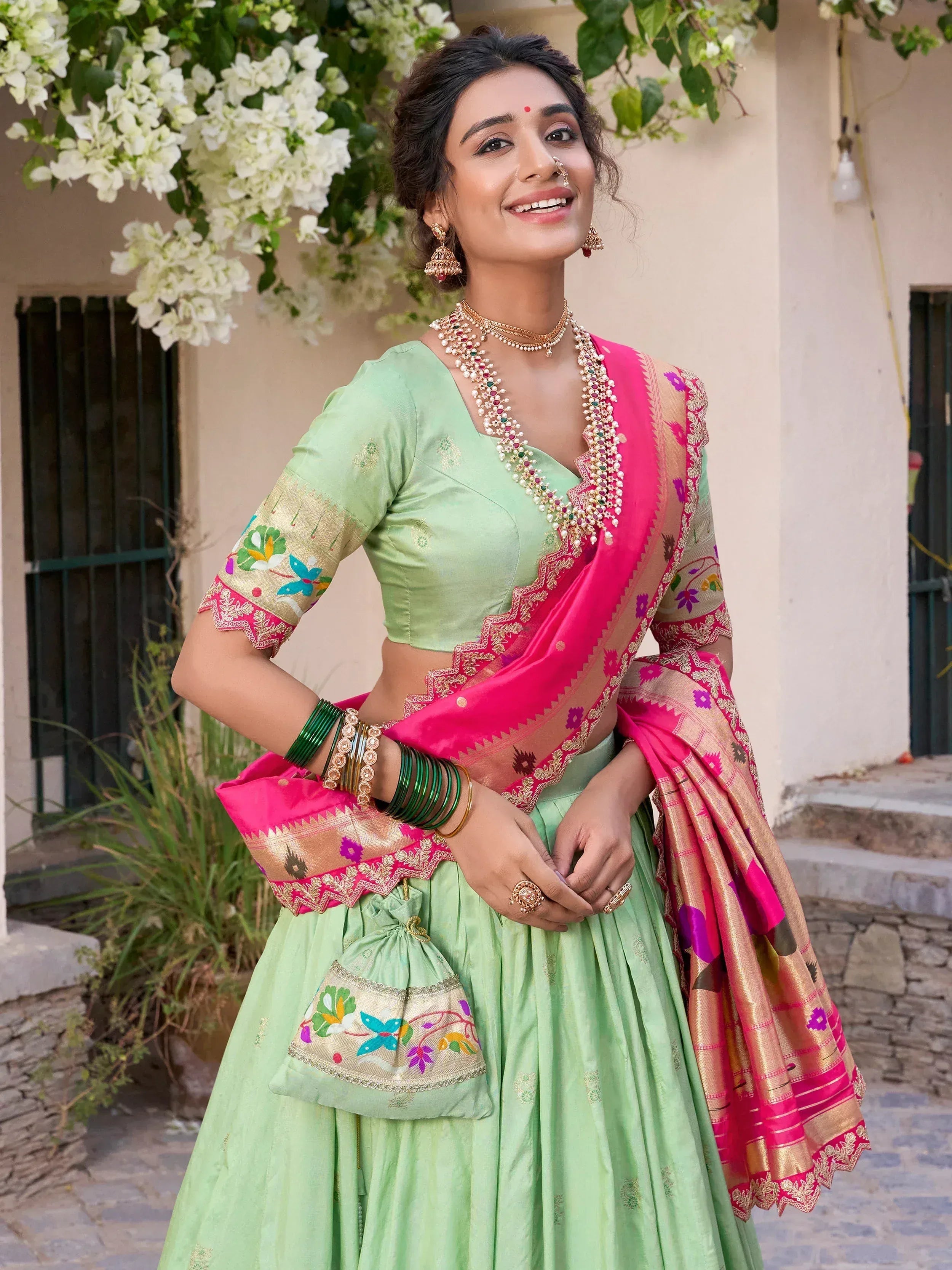 Mint green lehenga choli with pink dupatta, floral embroidery, and traditional Indian jewelry for festive occasions