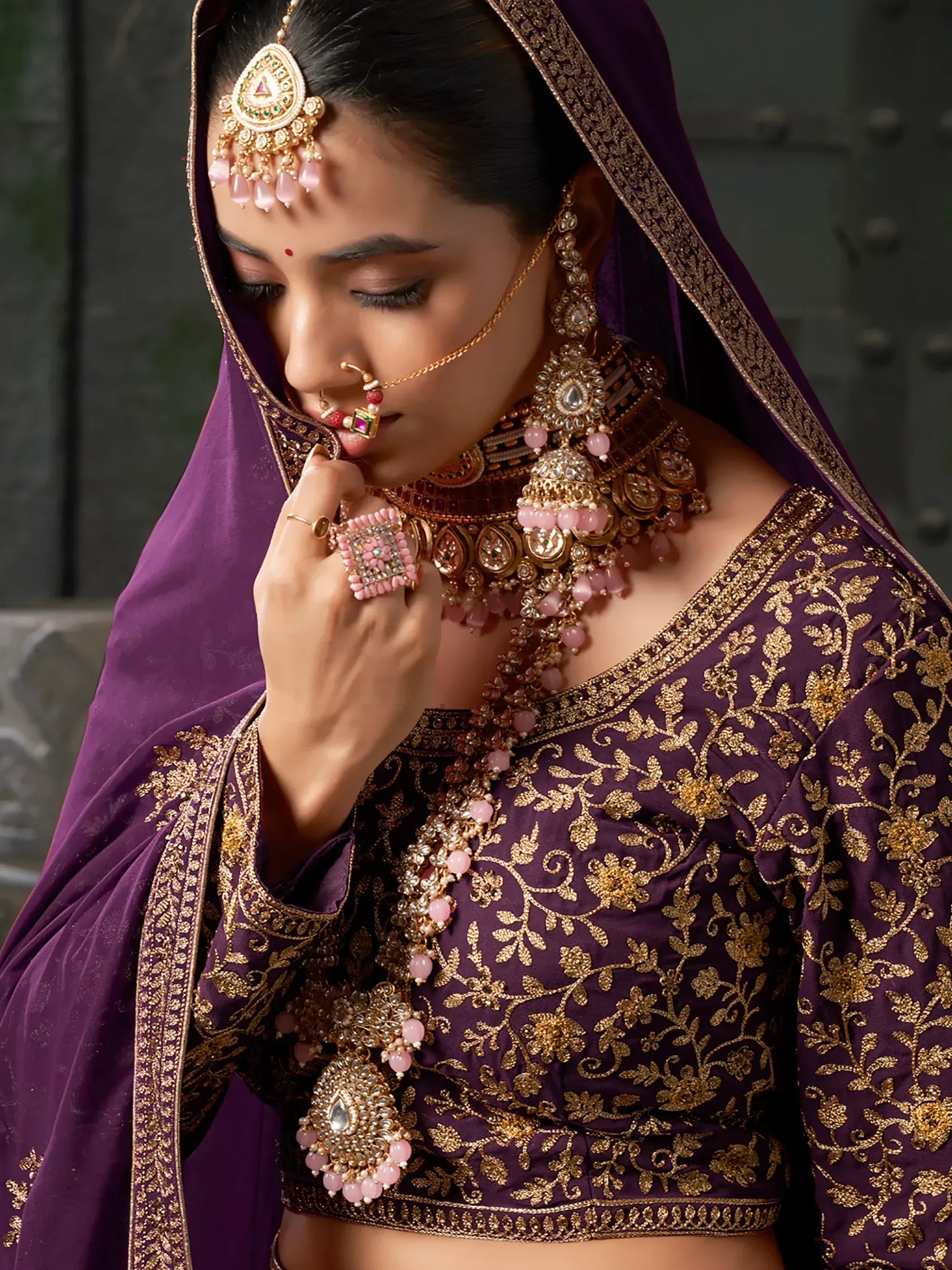Purple embroidered lehenga choli with gold detailing and traditional Indian bridal jewelry