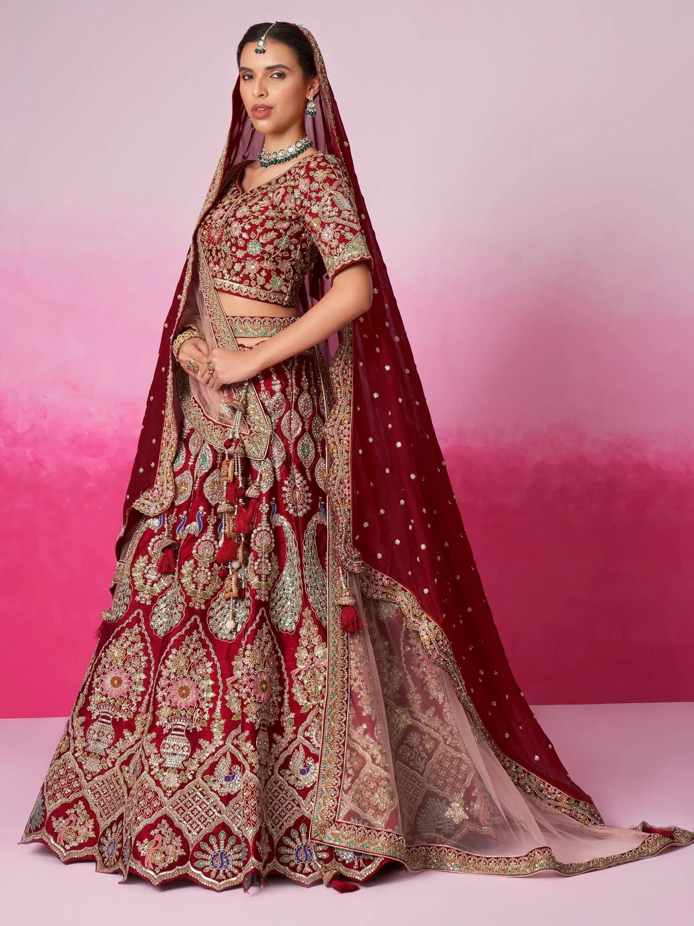 Elegant maroon lehenga choli with intricate gold embroidery and peacock motifs for Indian weddings