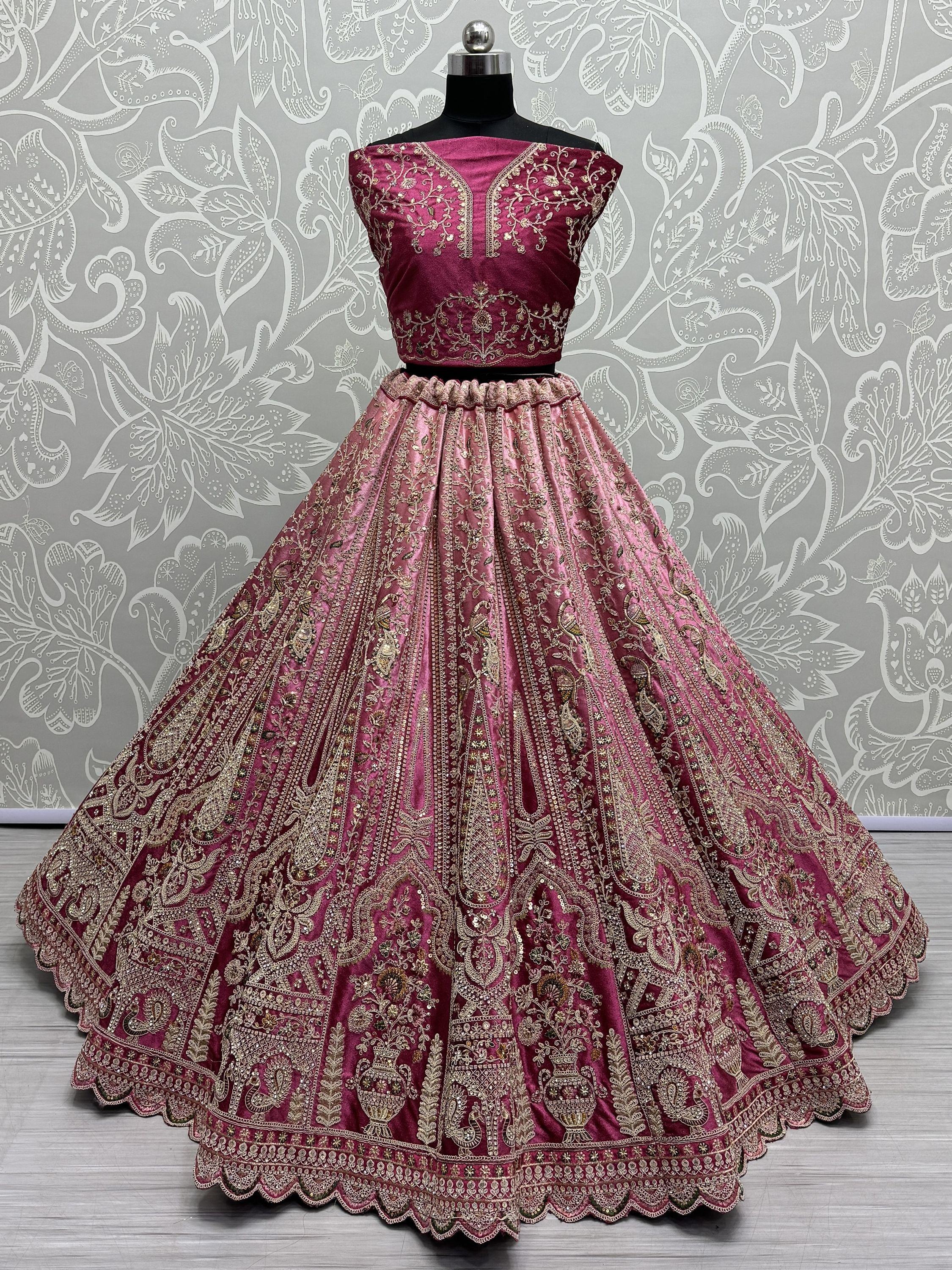 Pink embroidered lehenga choli with gold detailing, displayed on mannequin against floral backdrop