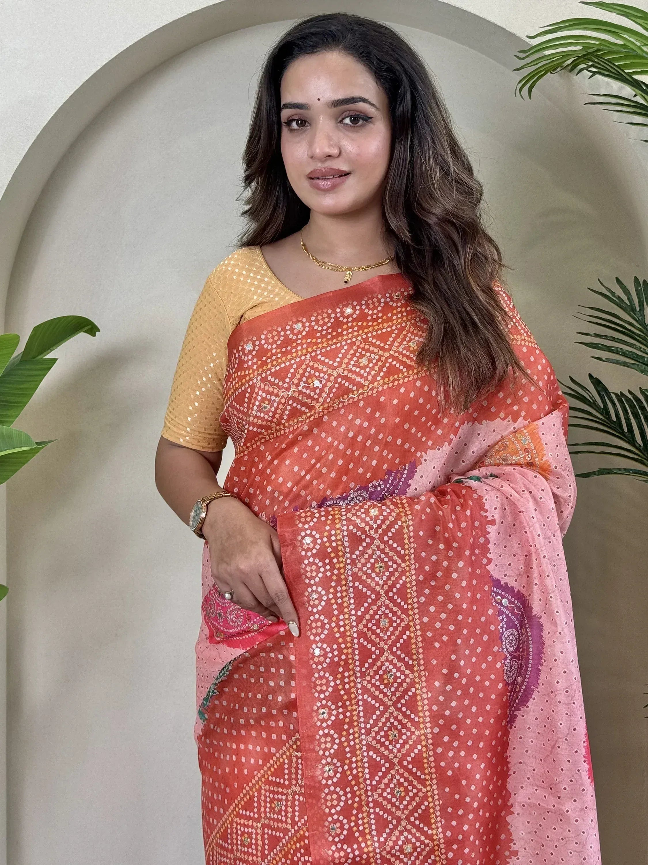 Woman in coral pink printed saree with sequin blouse, ethnic Indian wear