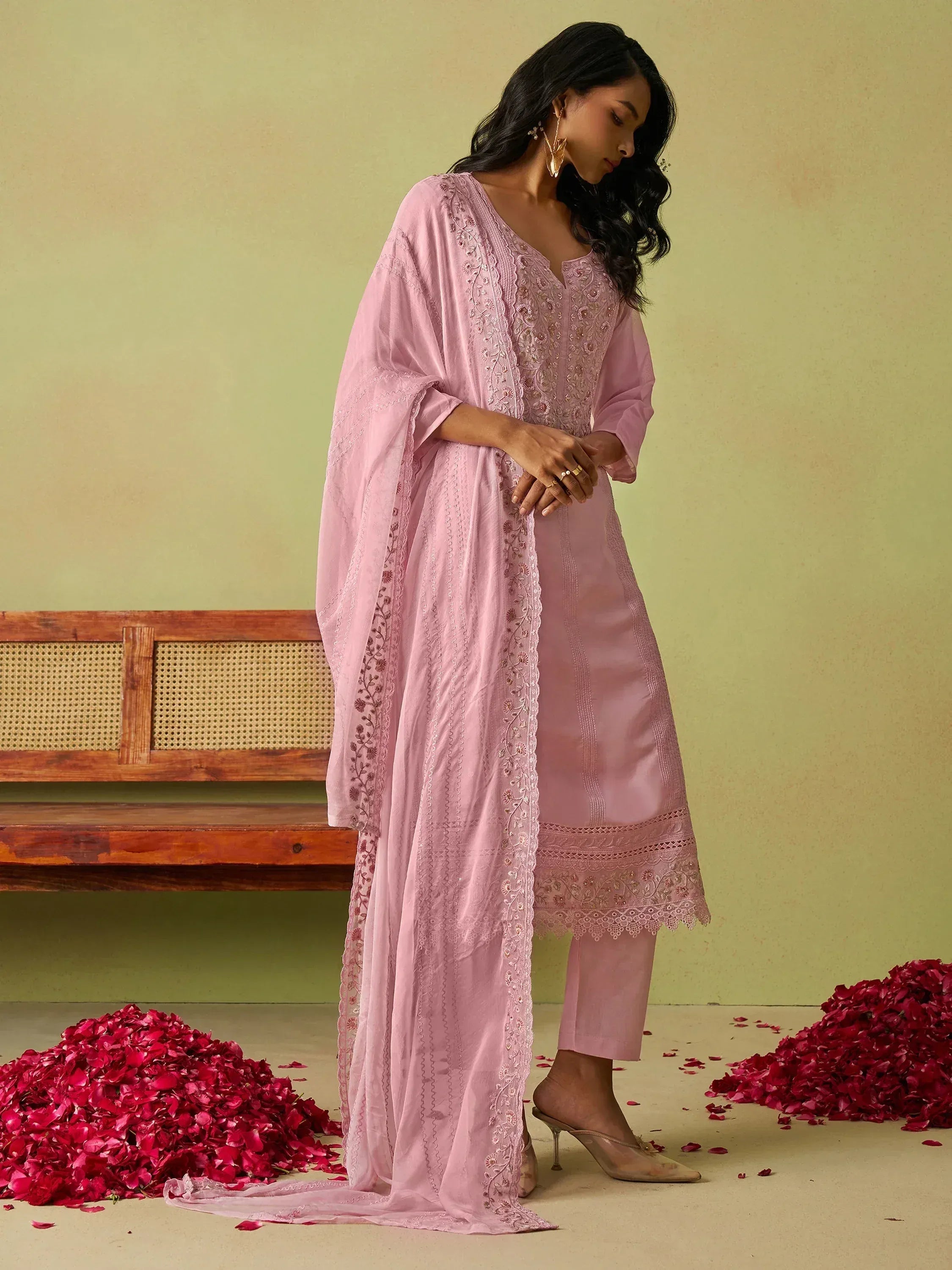 Pink embroidered salwar kameez with dupatta, floral details, and rose petals