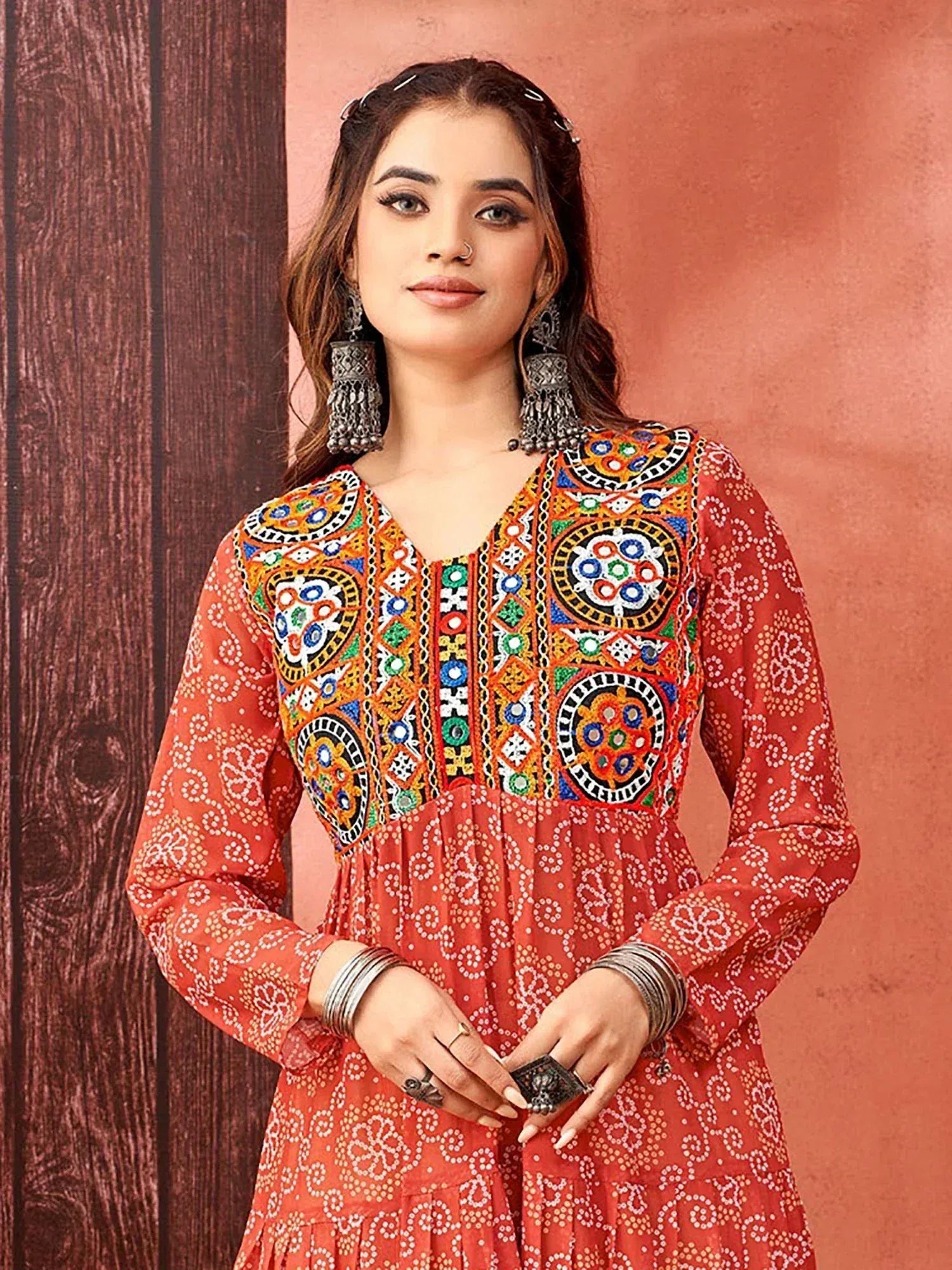 Woman in vibrant red ethnic kurti with colorful mirror work and white print, paired with statement jewelry