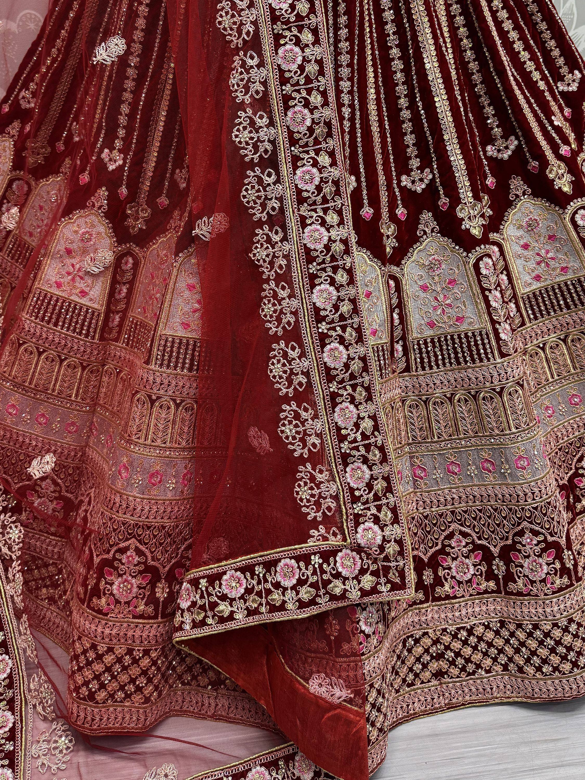 Luxury maroon velvet lehenga with intricate gold and pink floral embroidery, perfect for Indian weddings.