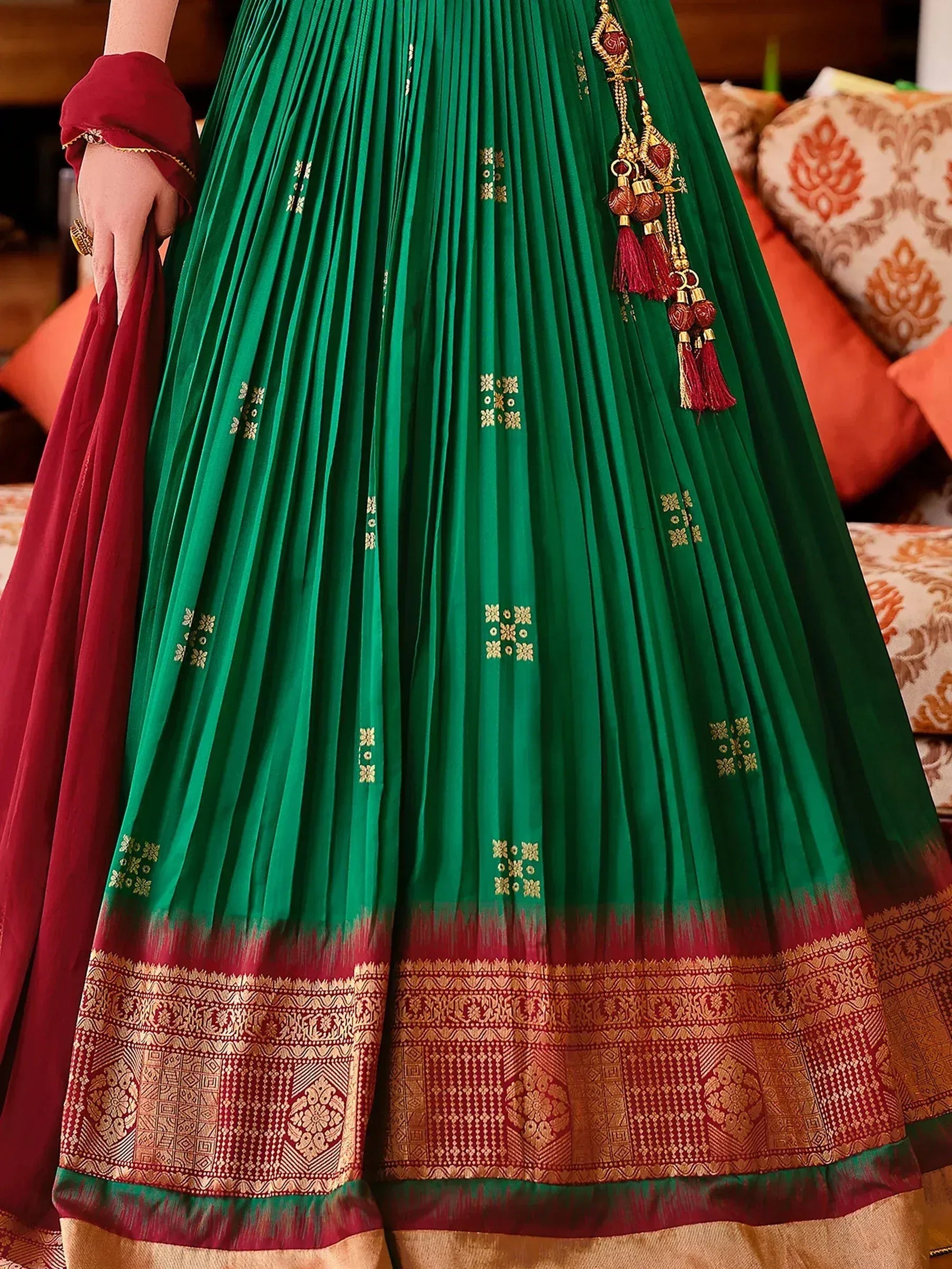 Green and maroon ethnic lehenga with gold embroidery and tassels, perfect for Indian weddings and festive occasions.