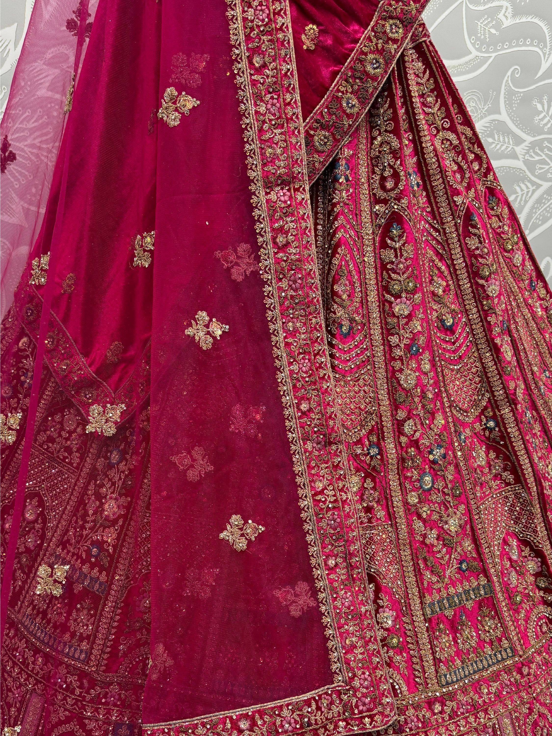 Luxury maroon velvet lehenga choli with intricate gold embroidery and floral motifs, perfect for Indian weddings.
