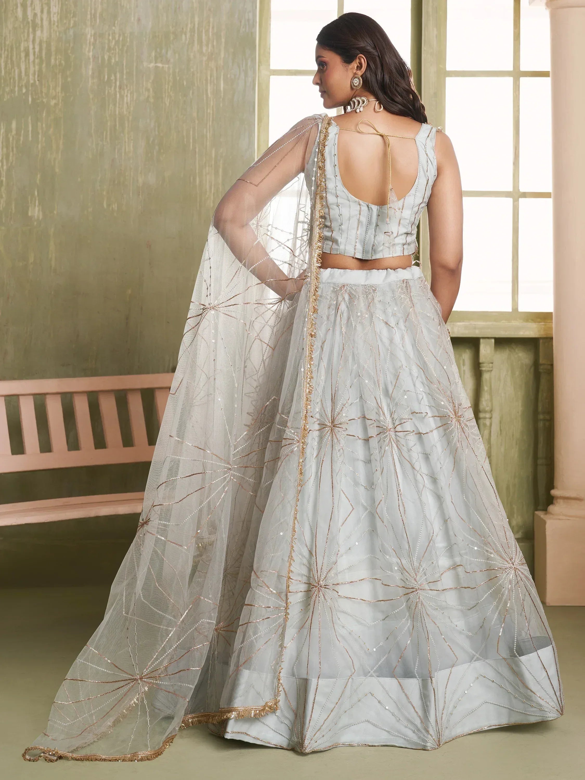Light blue designer lehenga choli with gold embroidery and sheer dupatta, perfect for Indian weddings and festive occasions.